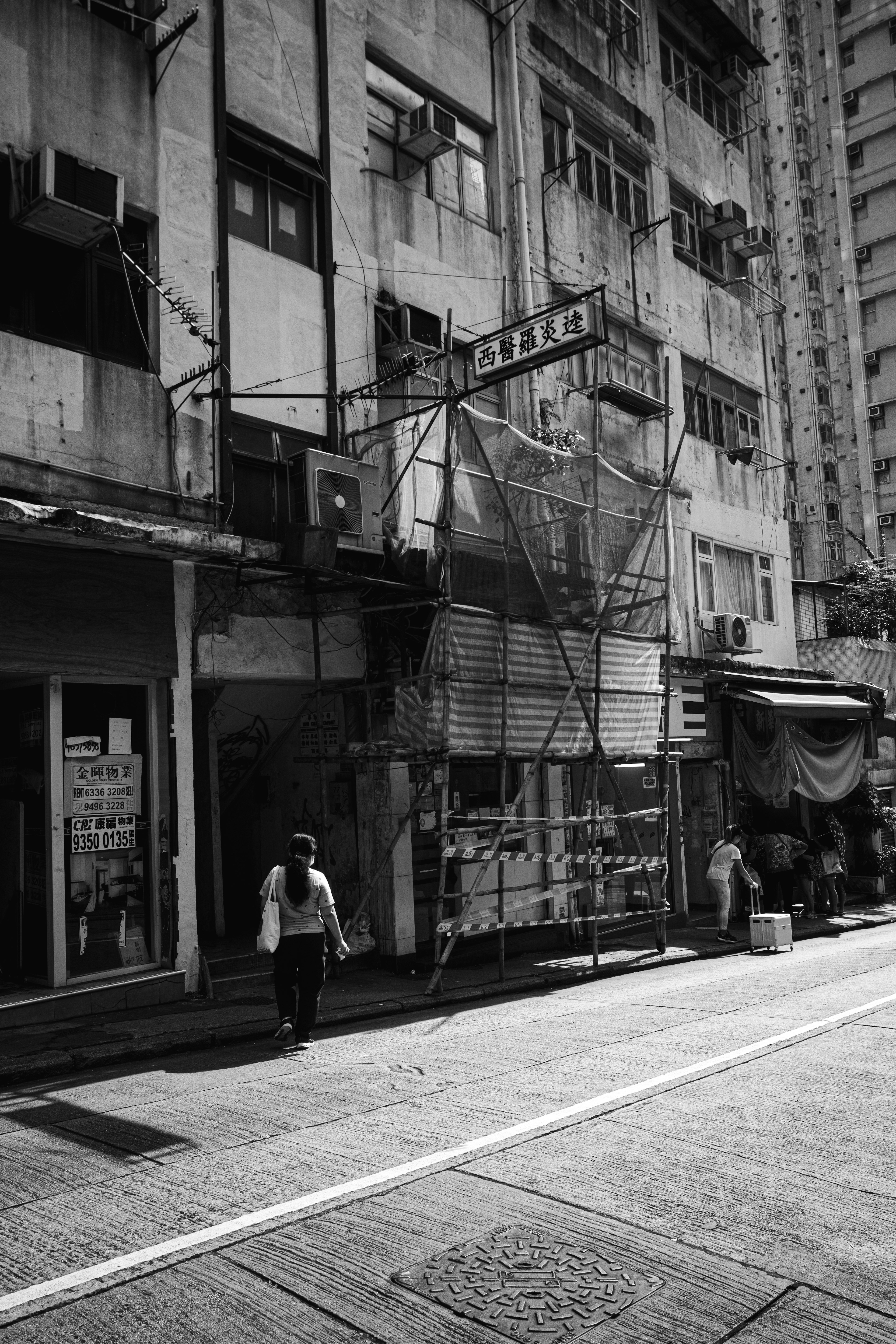 Scène de rue en noir et blanc avec des bâtiments anciens et un piéton