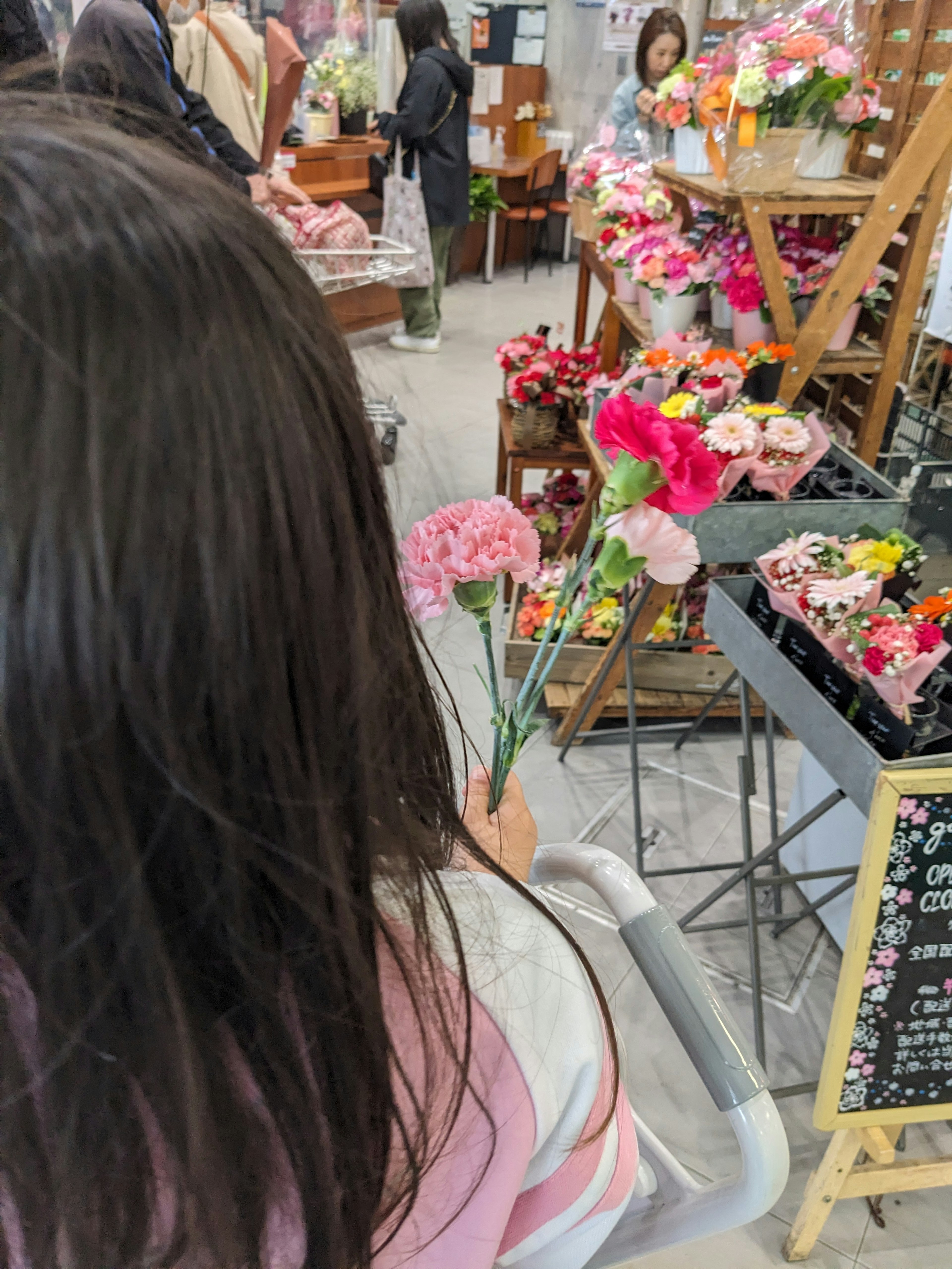 Niña sosteniendo flores coloridas en una floristería