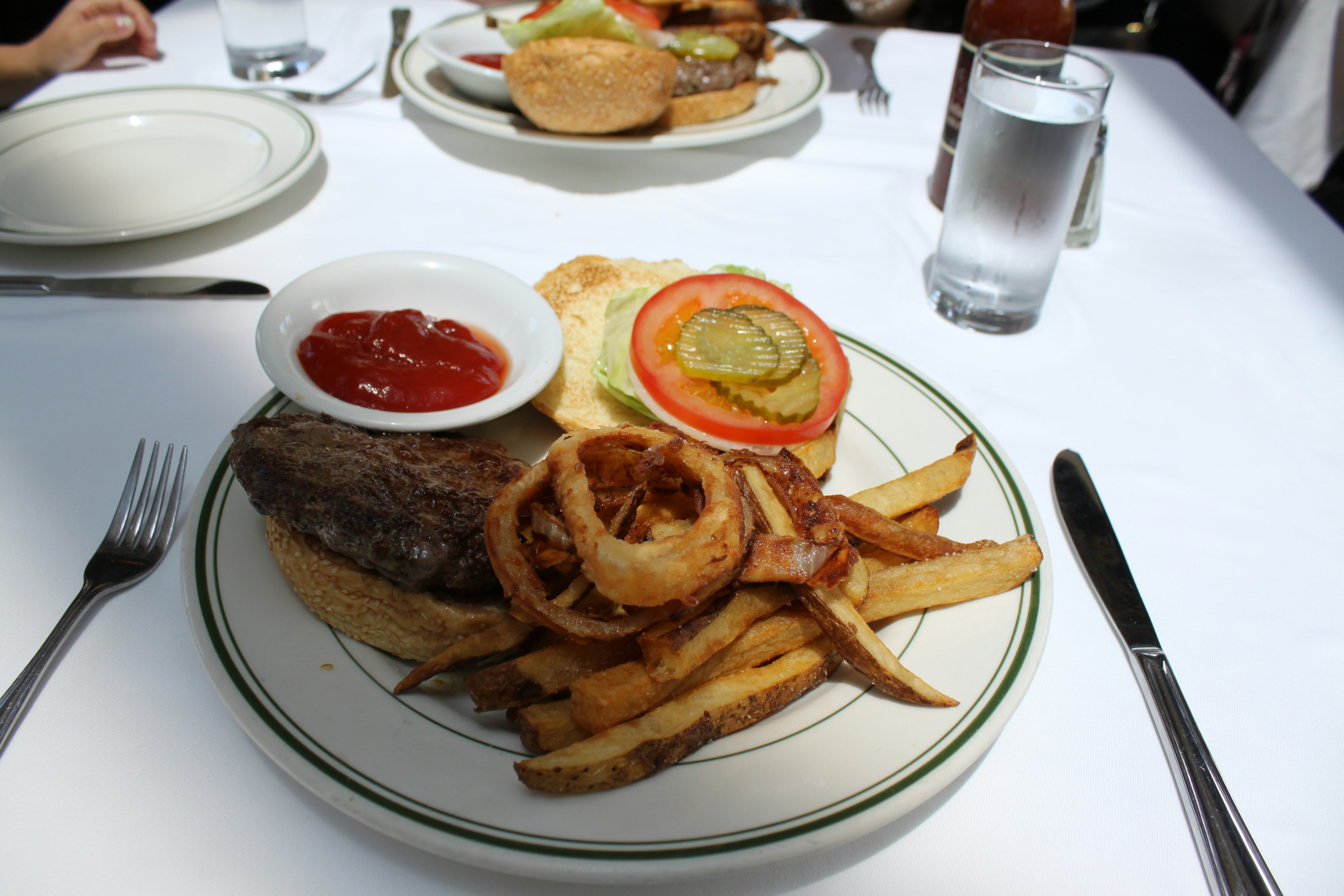 Dicker Hamburger mit Pommes und Zwiebelringen auf einem Teller