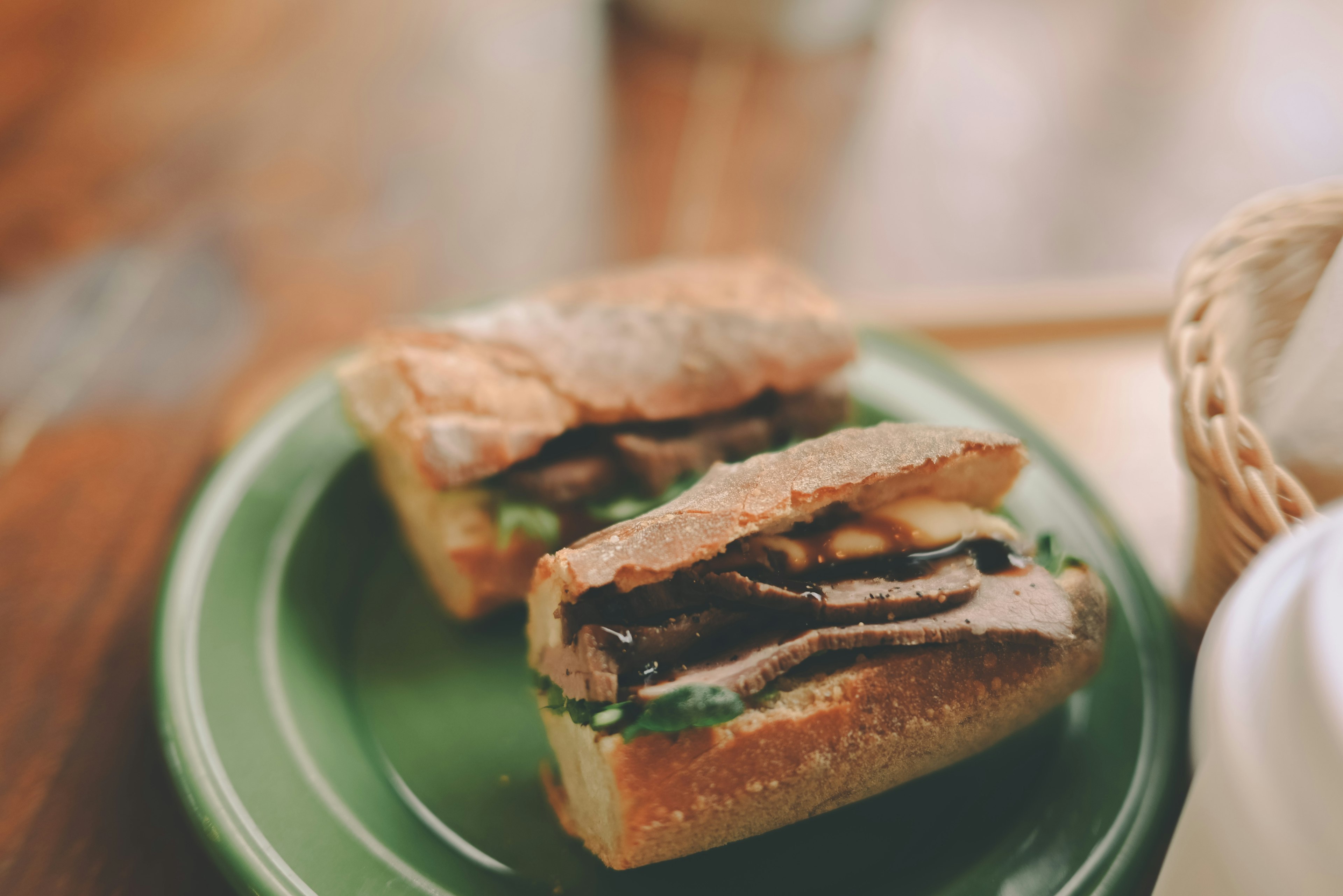 A sandwich with beef and greens on a green plate