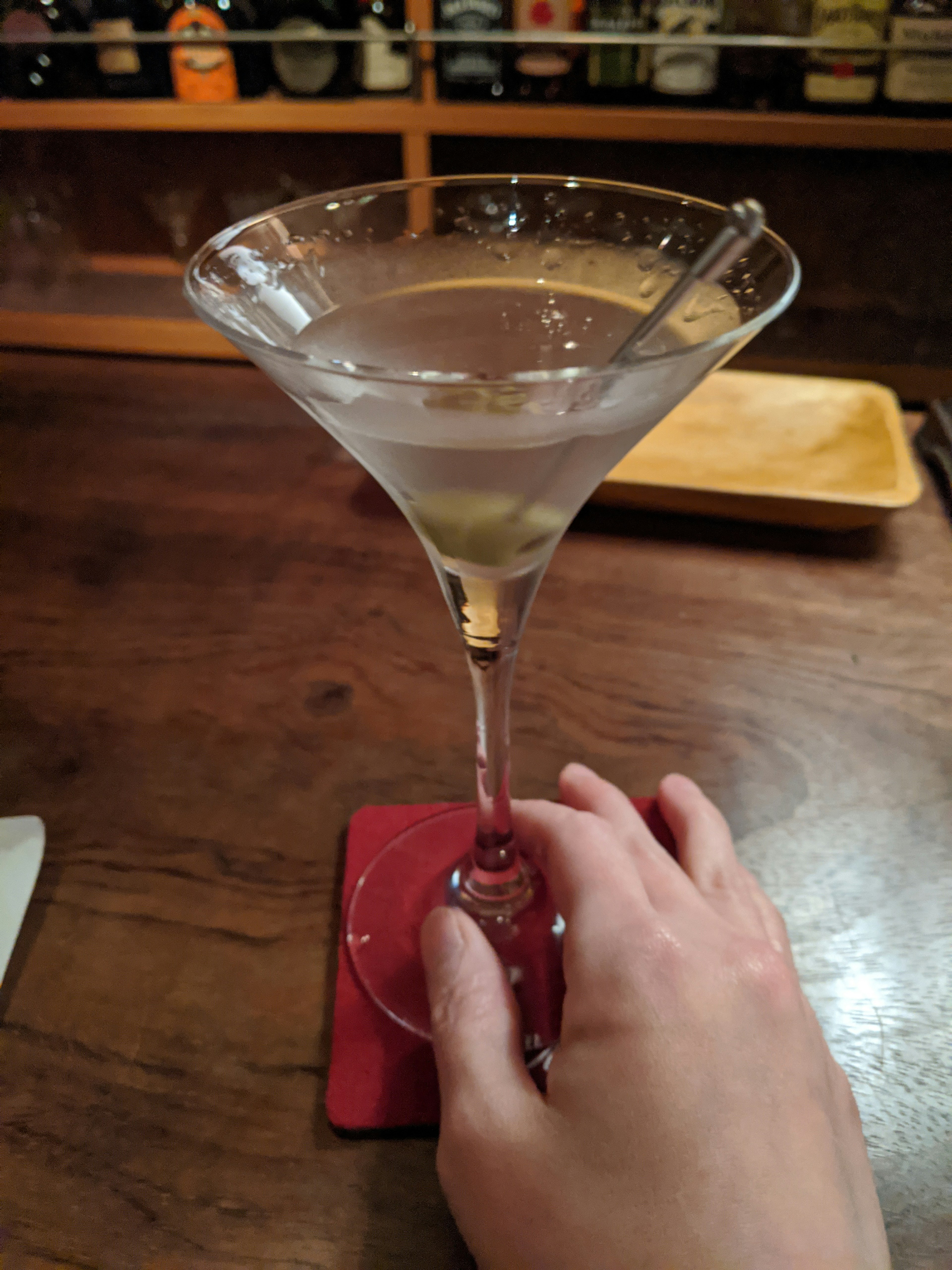 A martini in a cocktail glass with a hand holding it