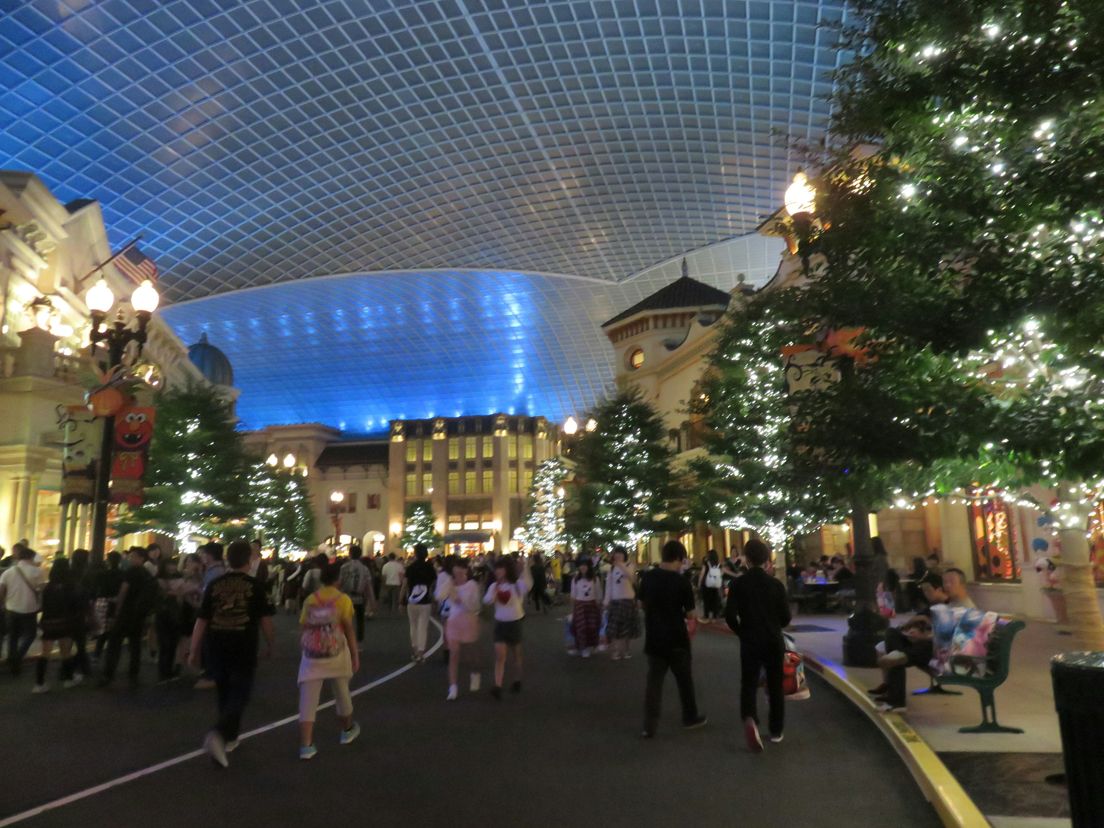 People enjoying a festive atmosphere with illuminated Christmas trees and a blue ceiling