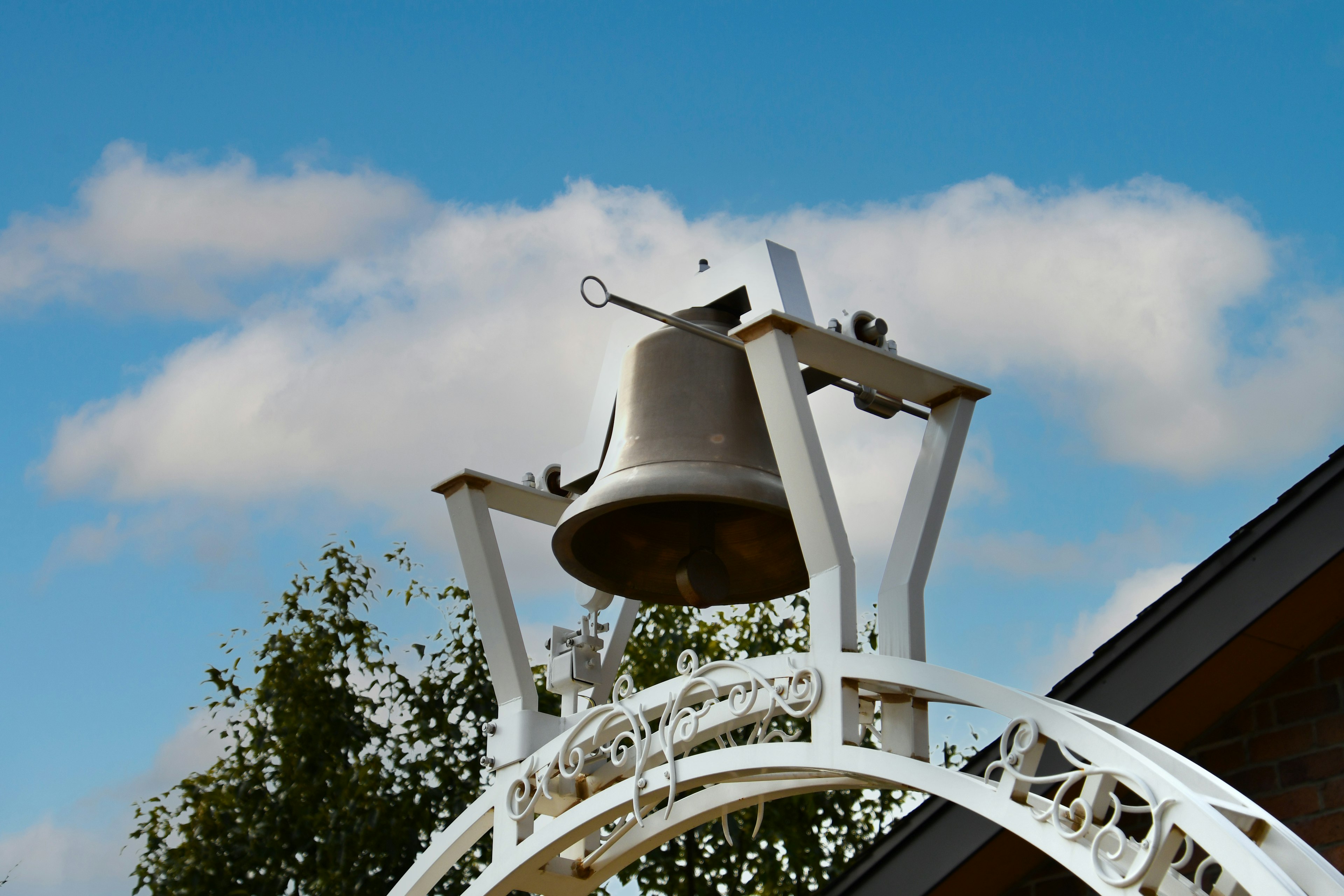 Une grande cloche sous un ciel bleu avec une structure d'arc blanc