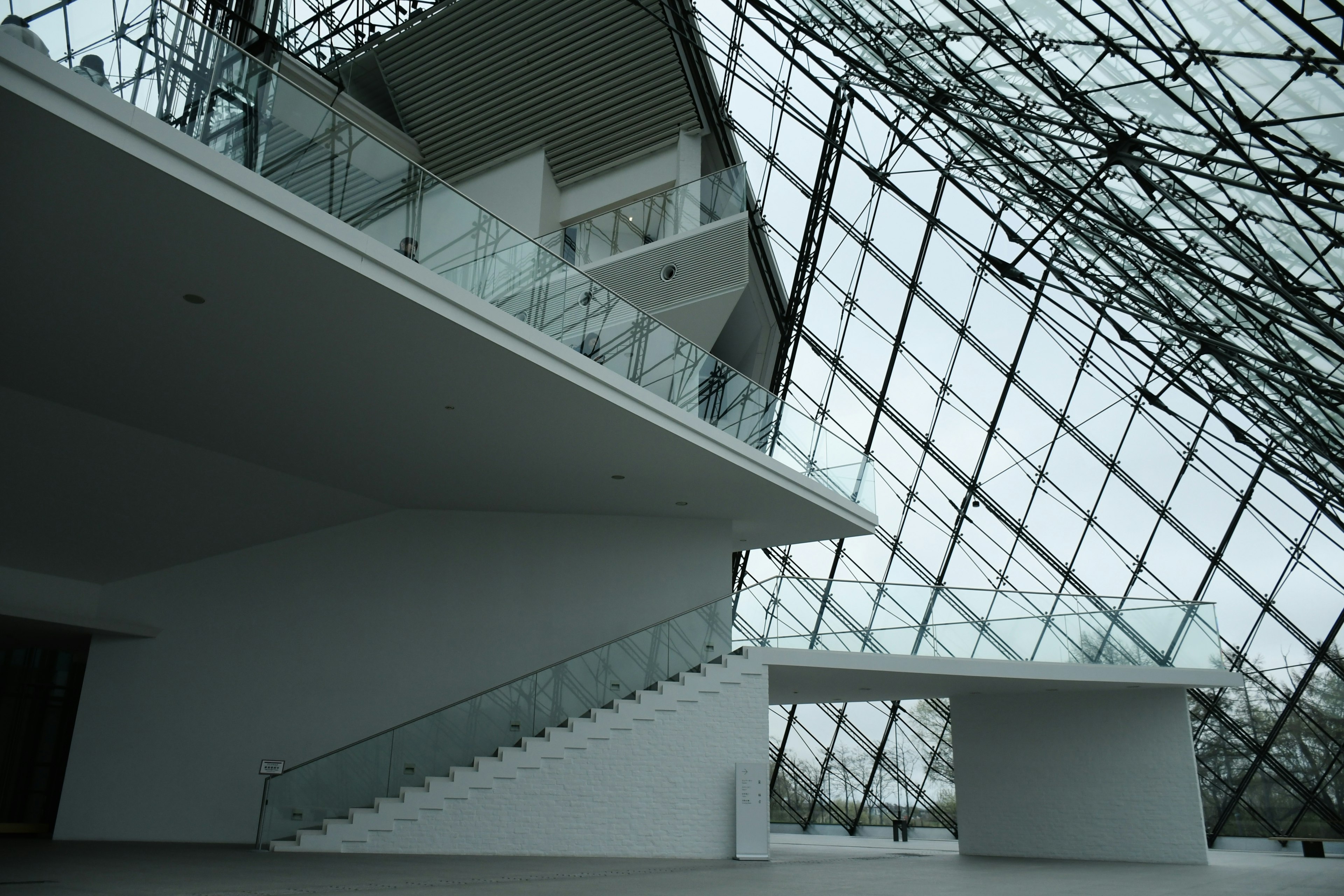 Escalier intérieur du musée du Louvre avec plafond en verre et murs blancs