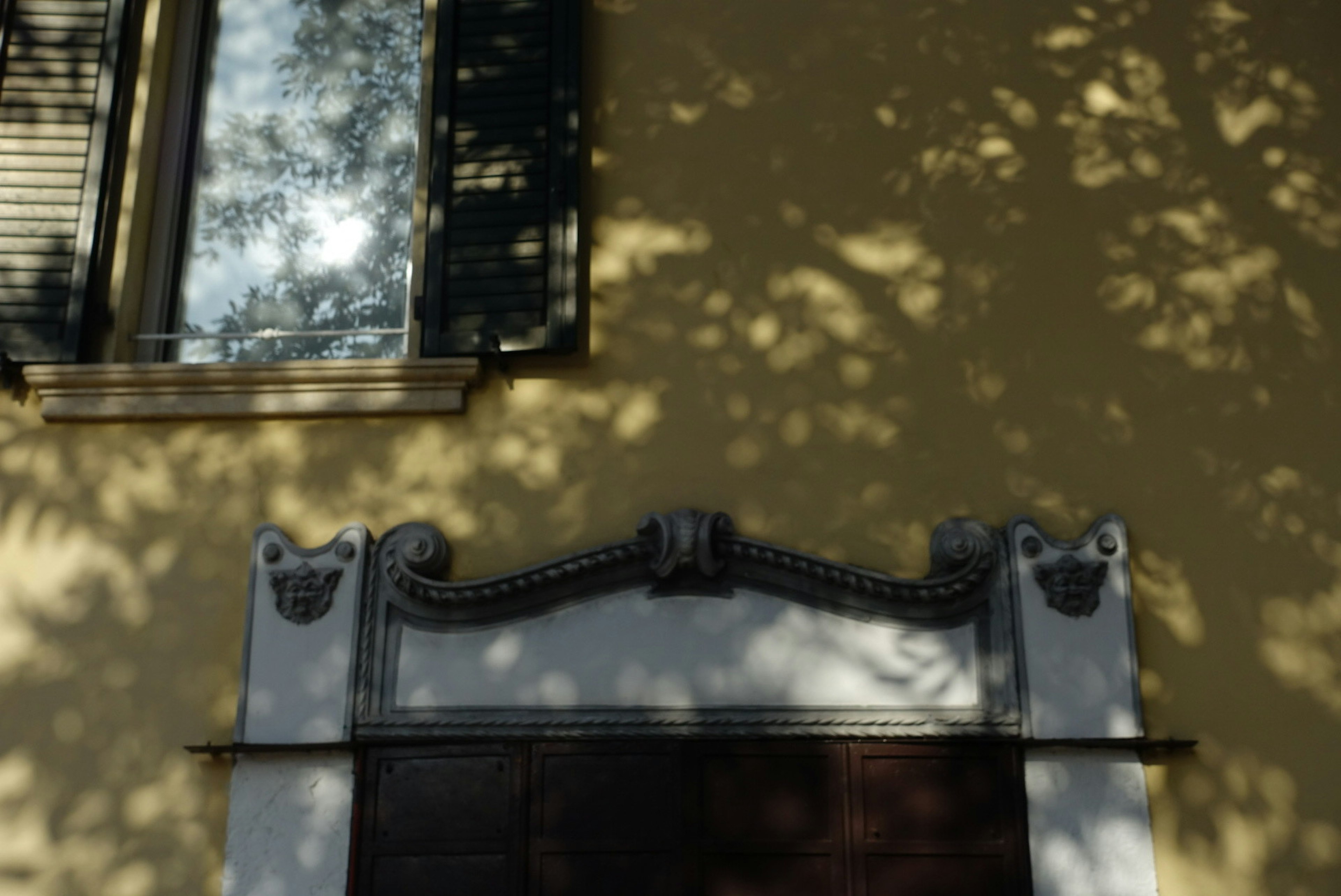 Parte di un edificio con un muro giallo e ombre di finestre