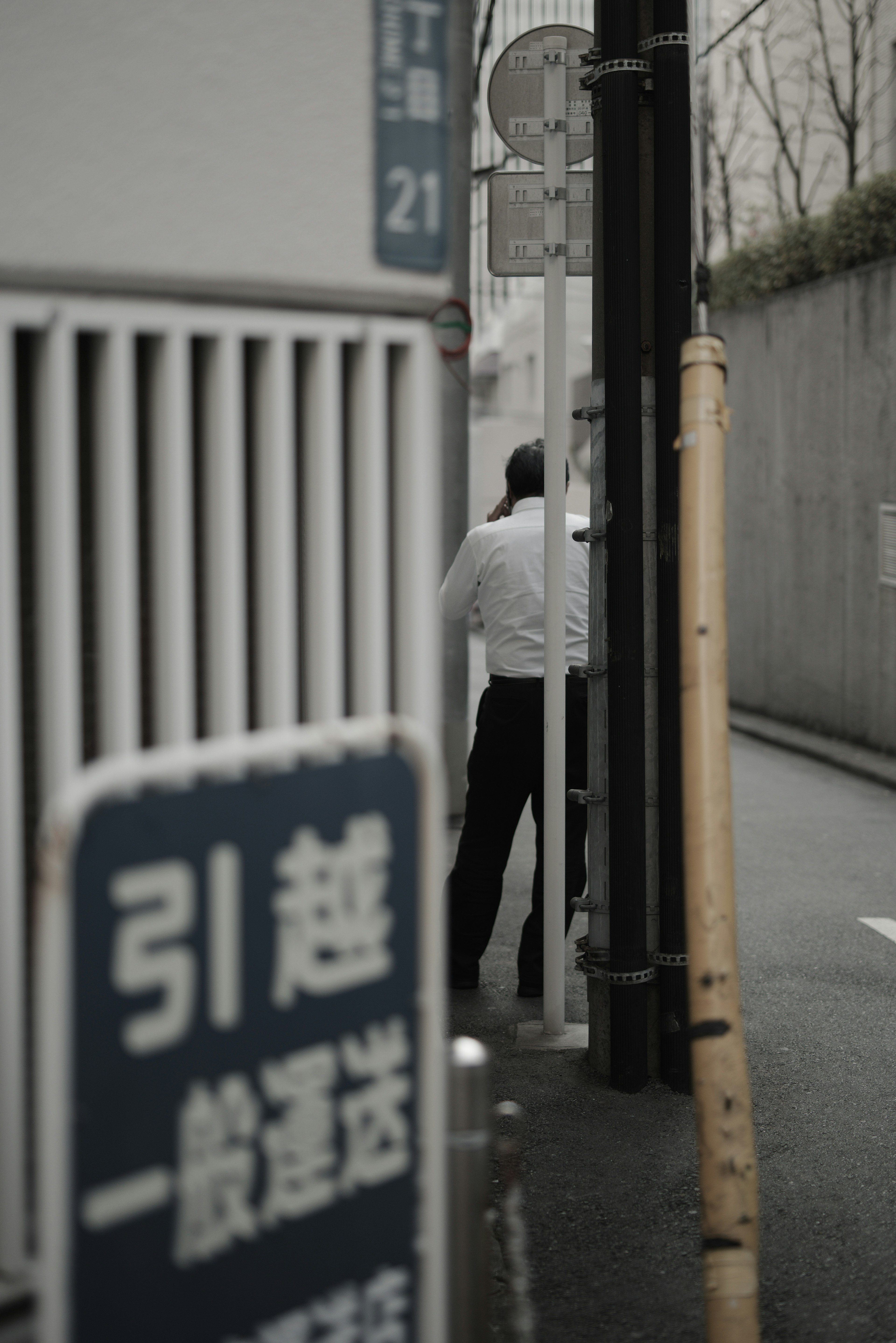 A man standing with his back in a narrow alley with a sign