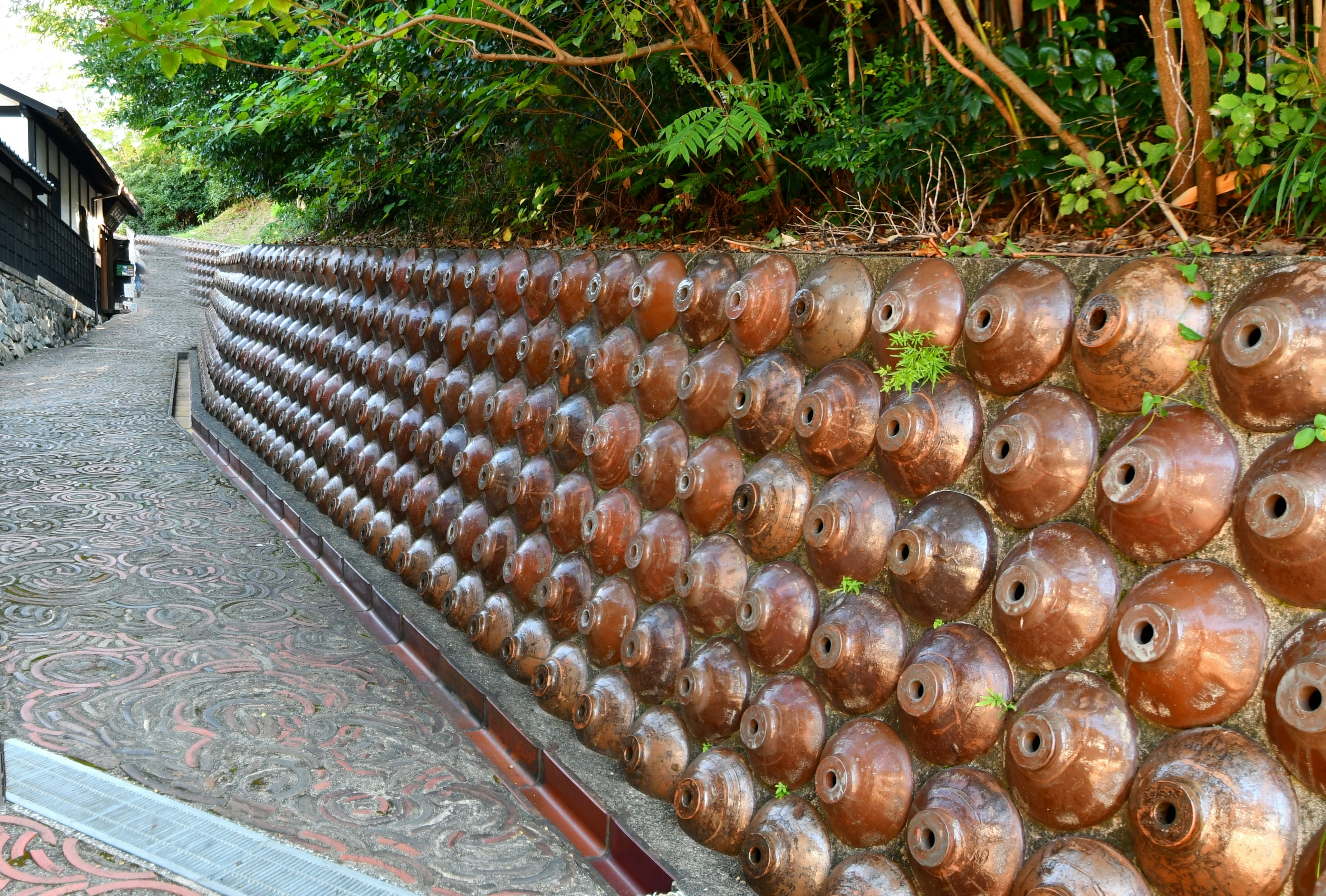 A scenic pathway lined with clay jars on a stone pavement