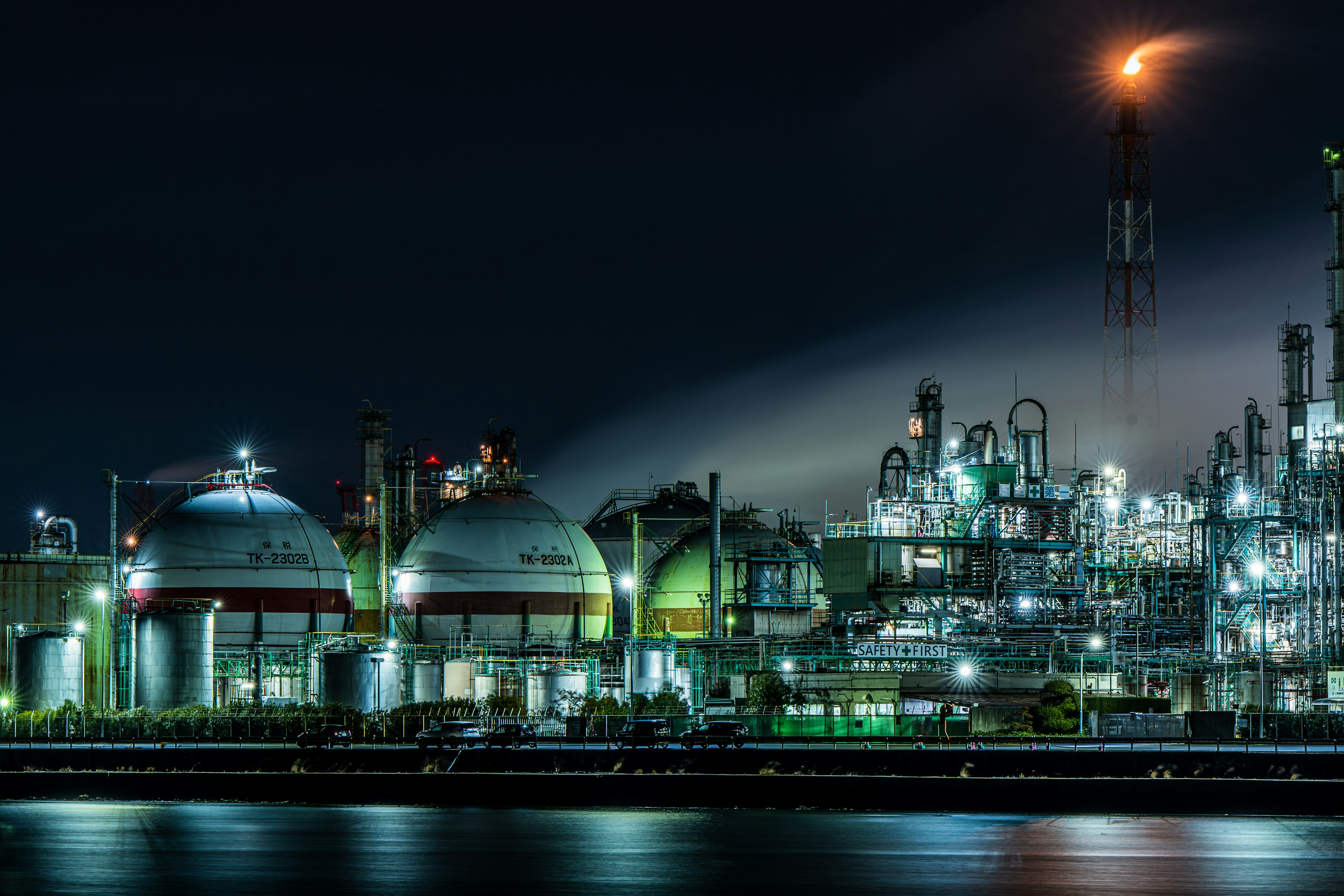 Nighttime industrial plant with gas tanks and smokestacks