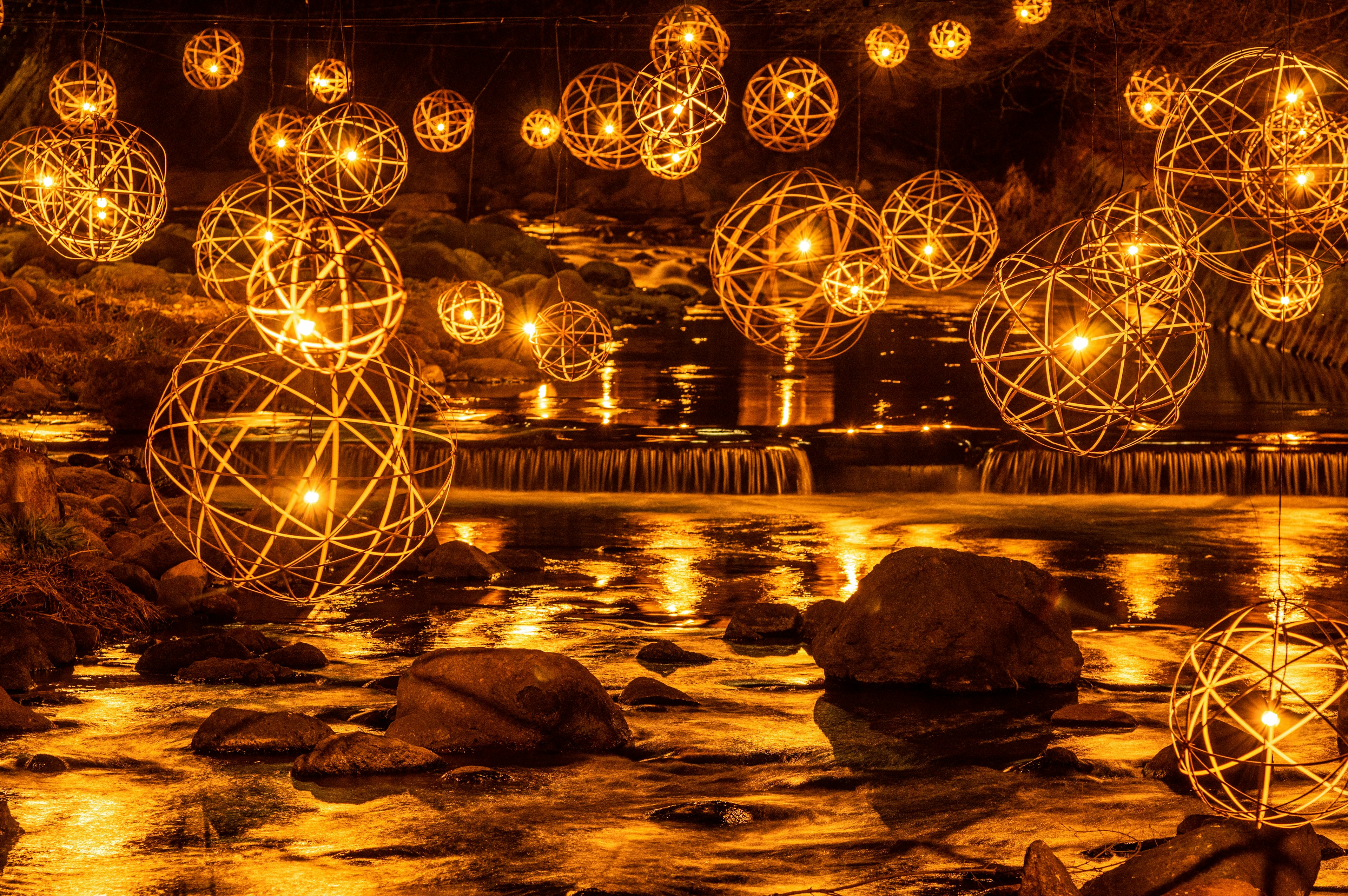 Una escena impresionante de esferas de luz doradas reflejándose en una superficie de agua tranquila