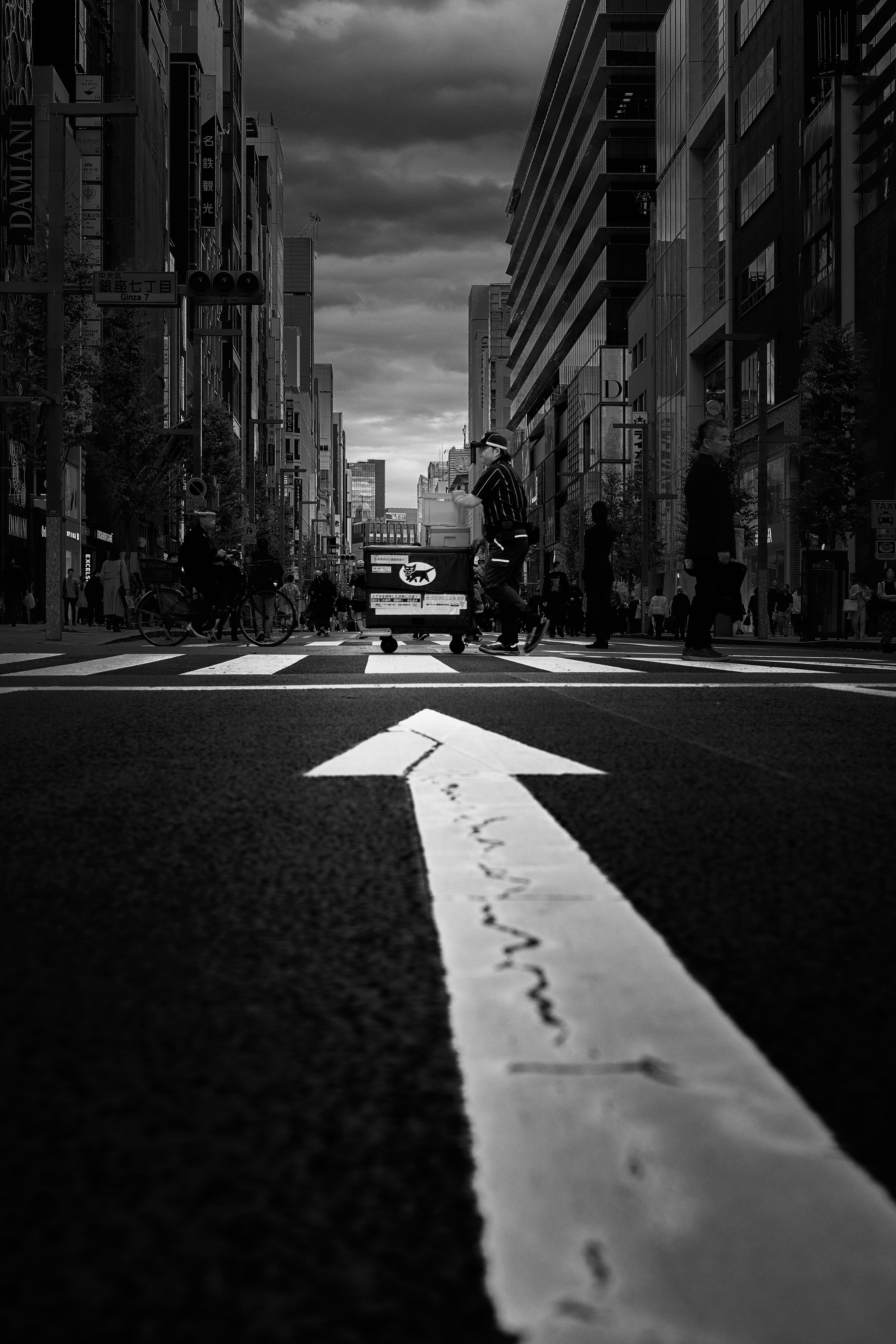 Paisaje urbano en blanco y negro con una flecha blanca en la carretera