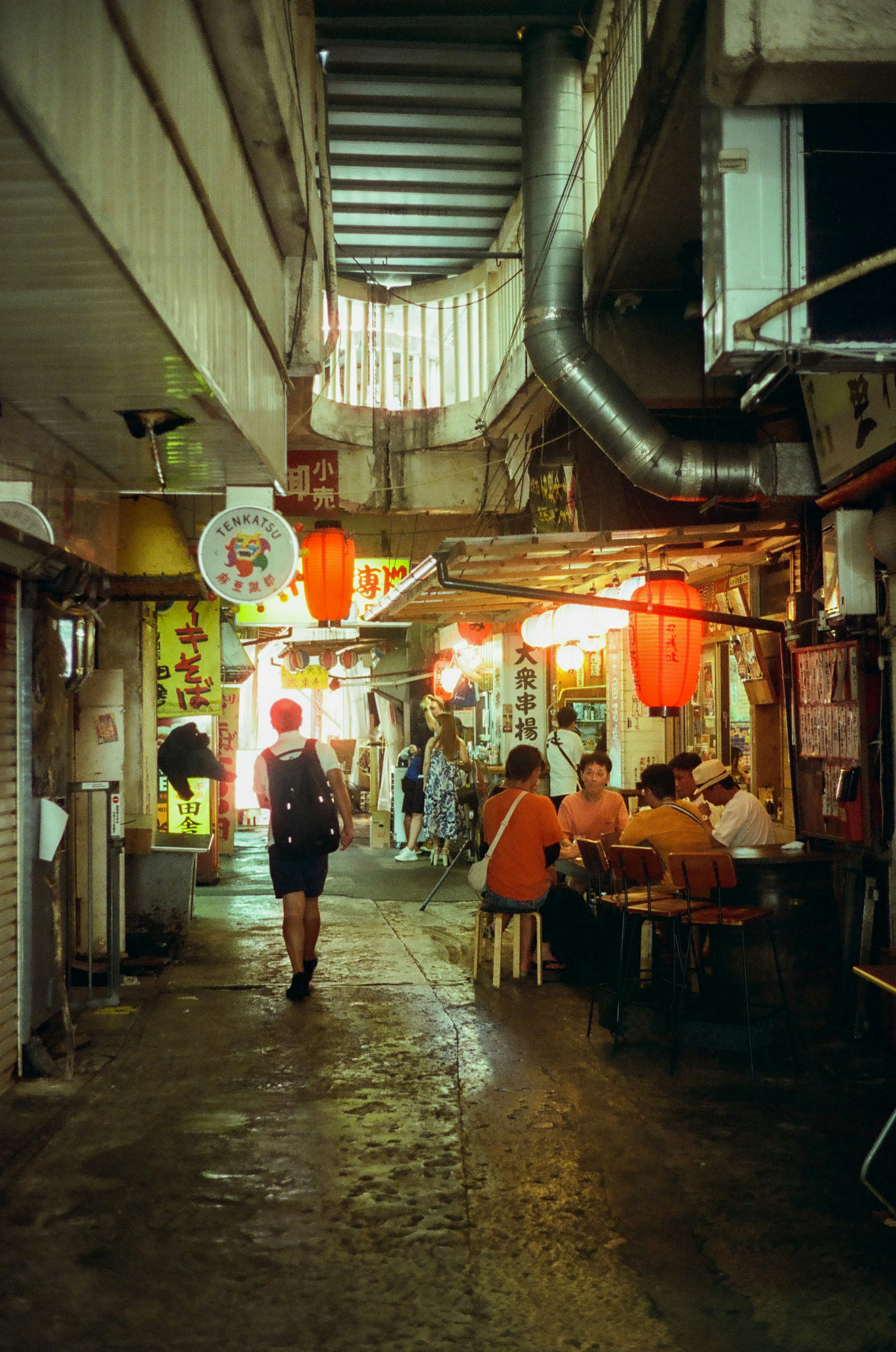 Schmale Gasse mit Straßenverkäufern und Laternen auf einem Nachtmarkt