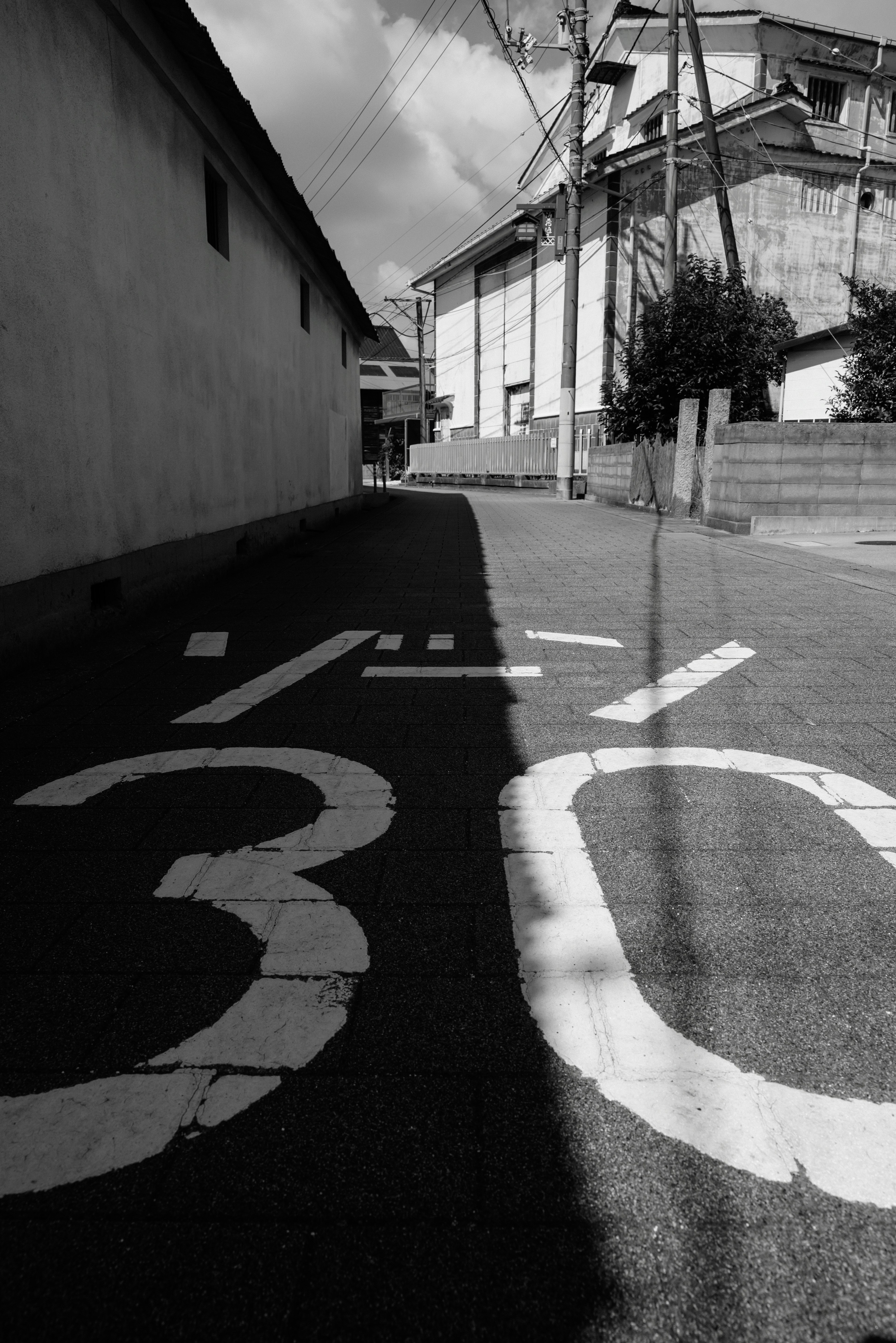 Rue en noir et blanc avec un panneau de limite de vitesse 30 peint et des bâtiments environnants