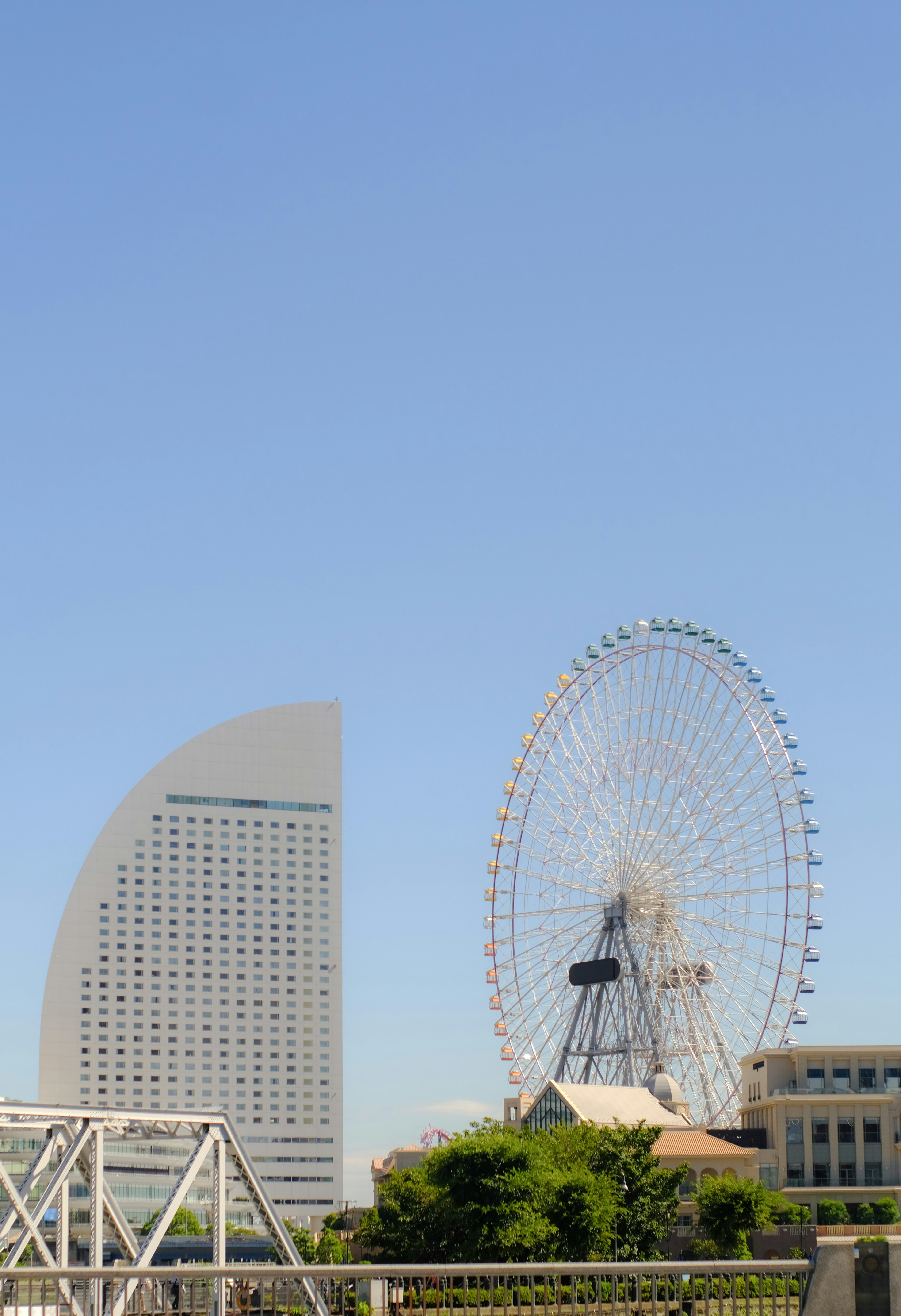 Panorama di Yokohama con la Landmark Tower e la ruota panoramica sotto un cielo azzurro