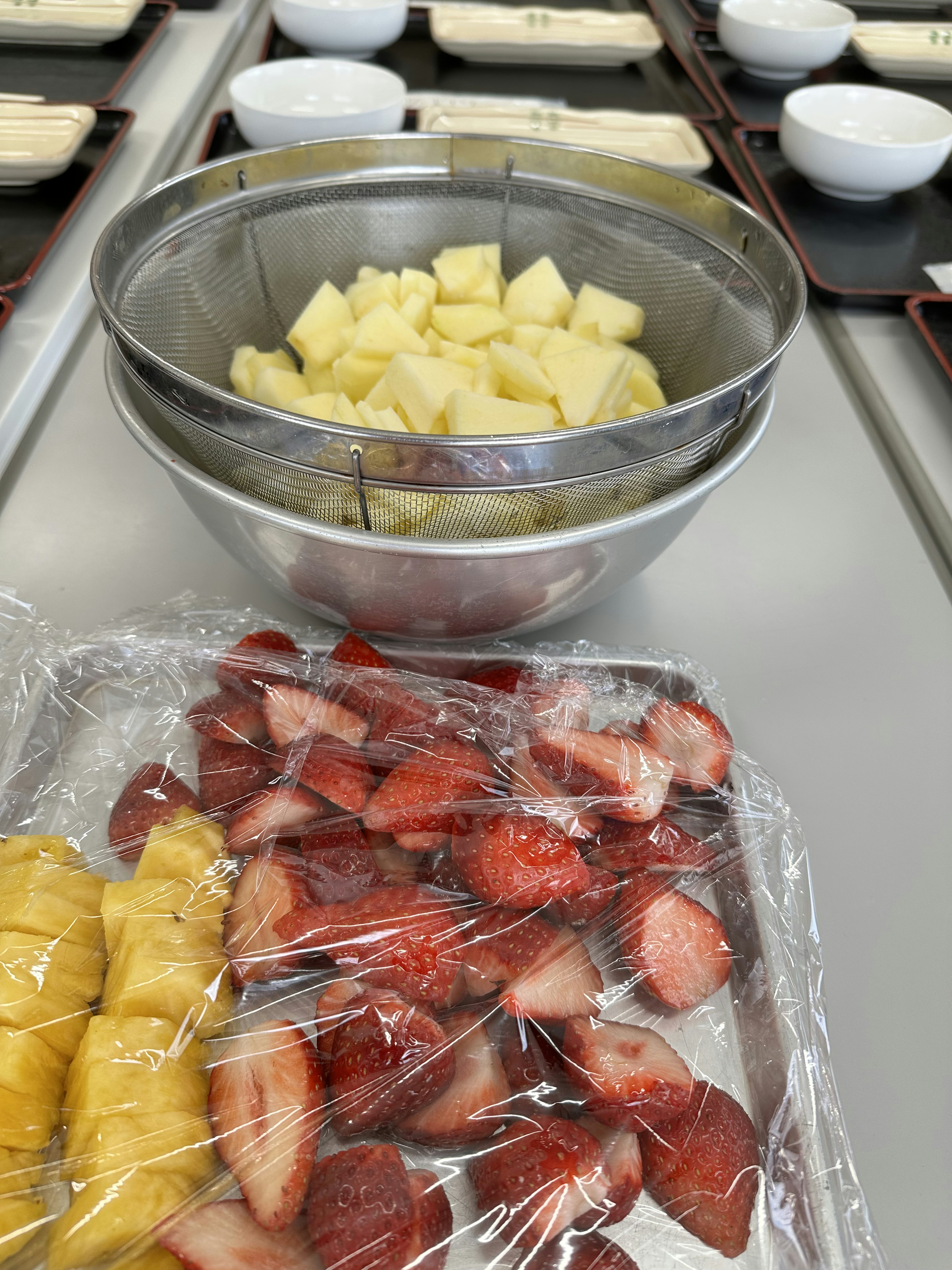 Image of cut pineapple and strawberries in a bowl and tray