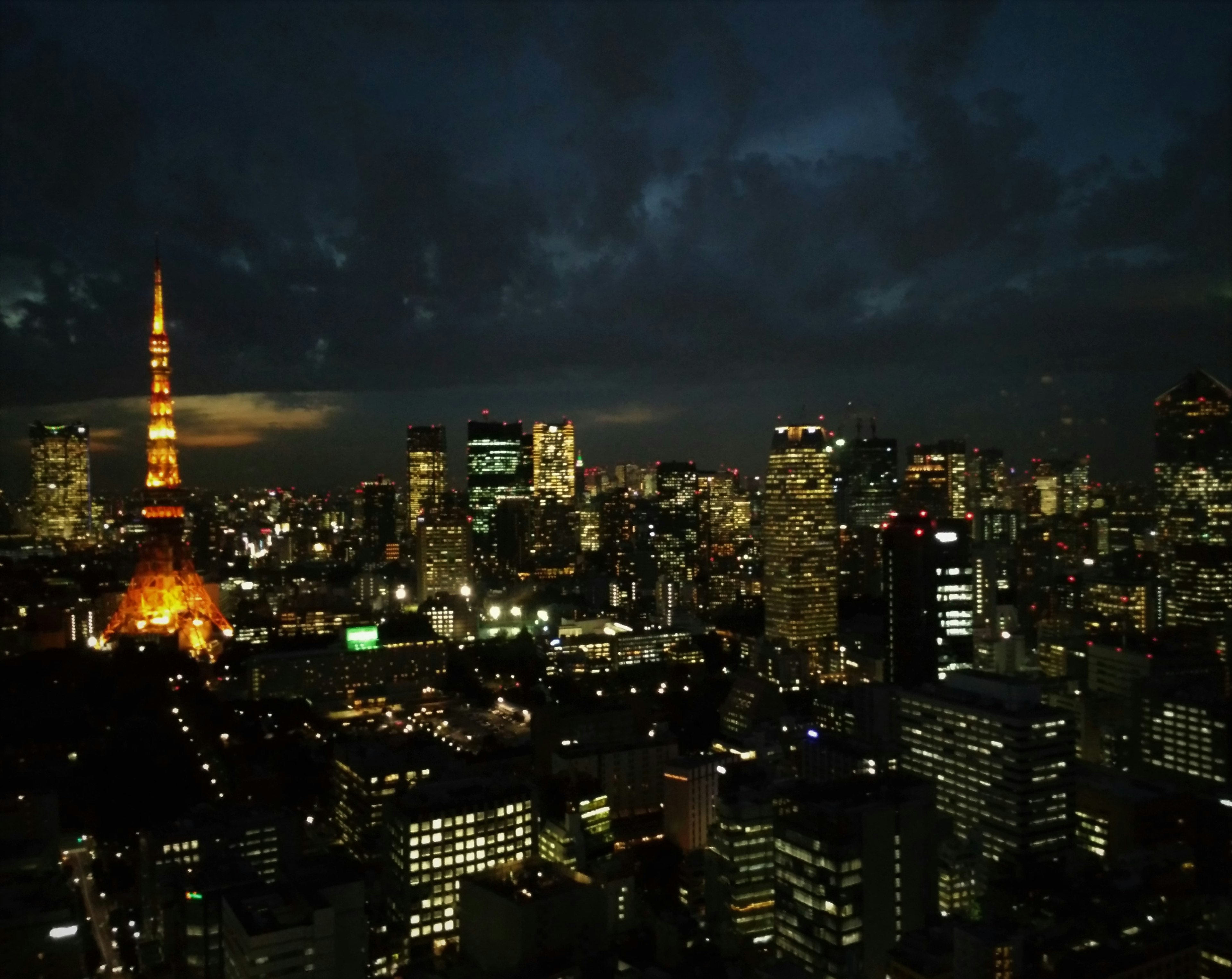 Tokyo Tower illuminated against the night skyline of Tokyo with skyscrapers