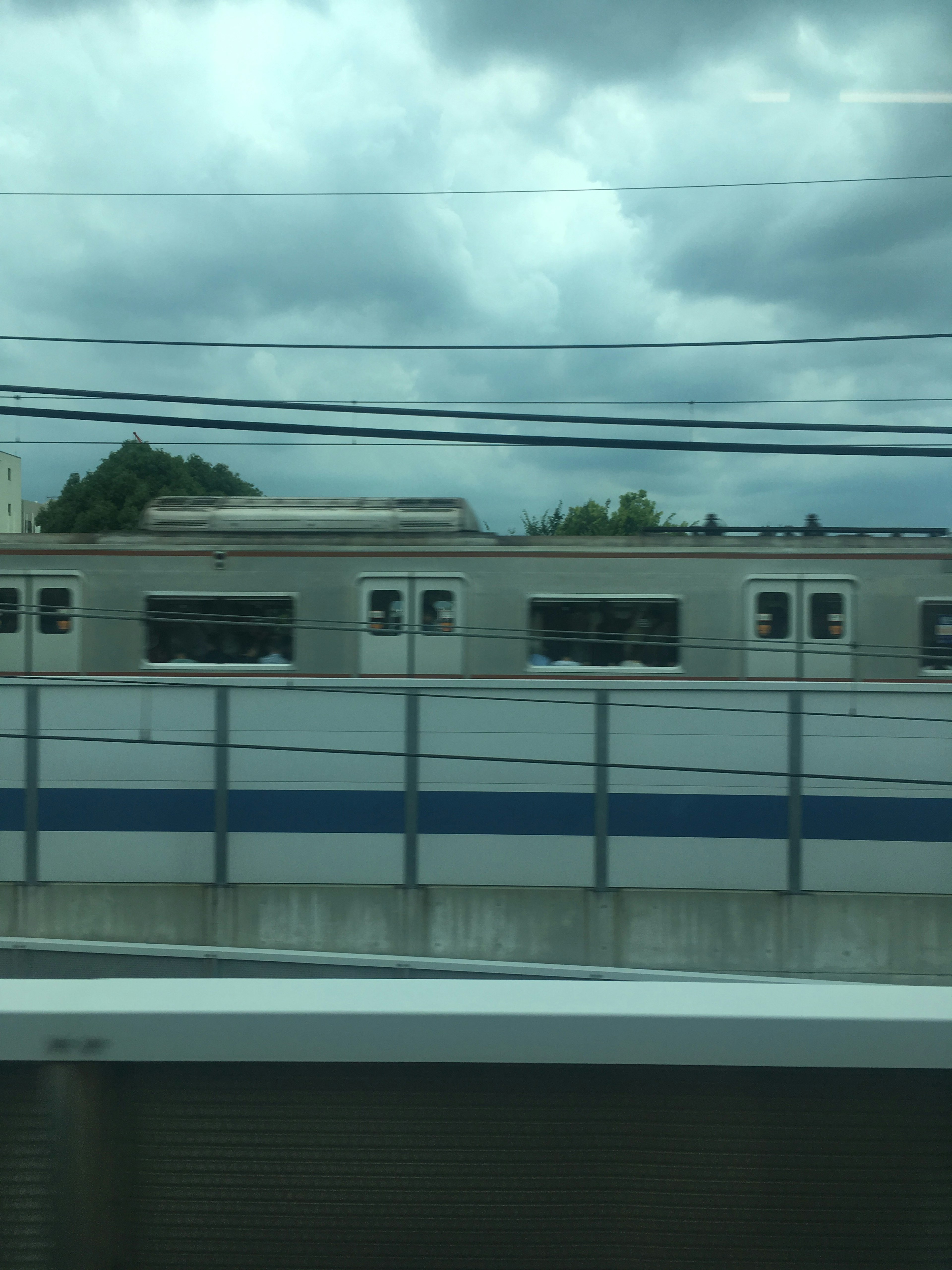 รถไฟที่วิ่งผ่านใต้ท้องฟ้าที่มีเมฆและโครงสร้างพื้นฐานทางรถไฟที่มองเห็นได้