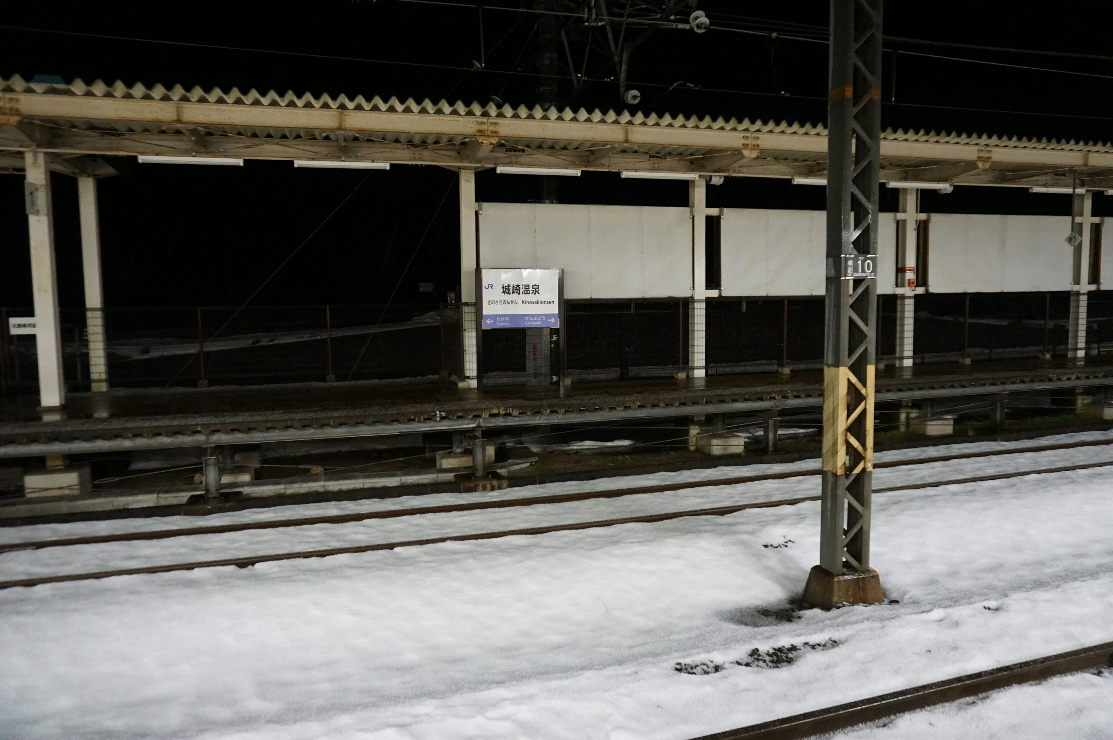 雪に覆われた駅のプラットフォームと線路が映る夜の風景