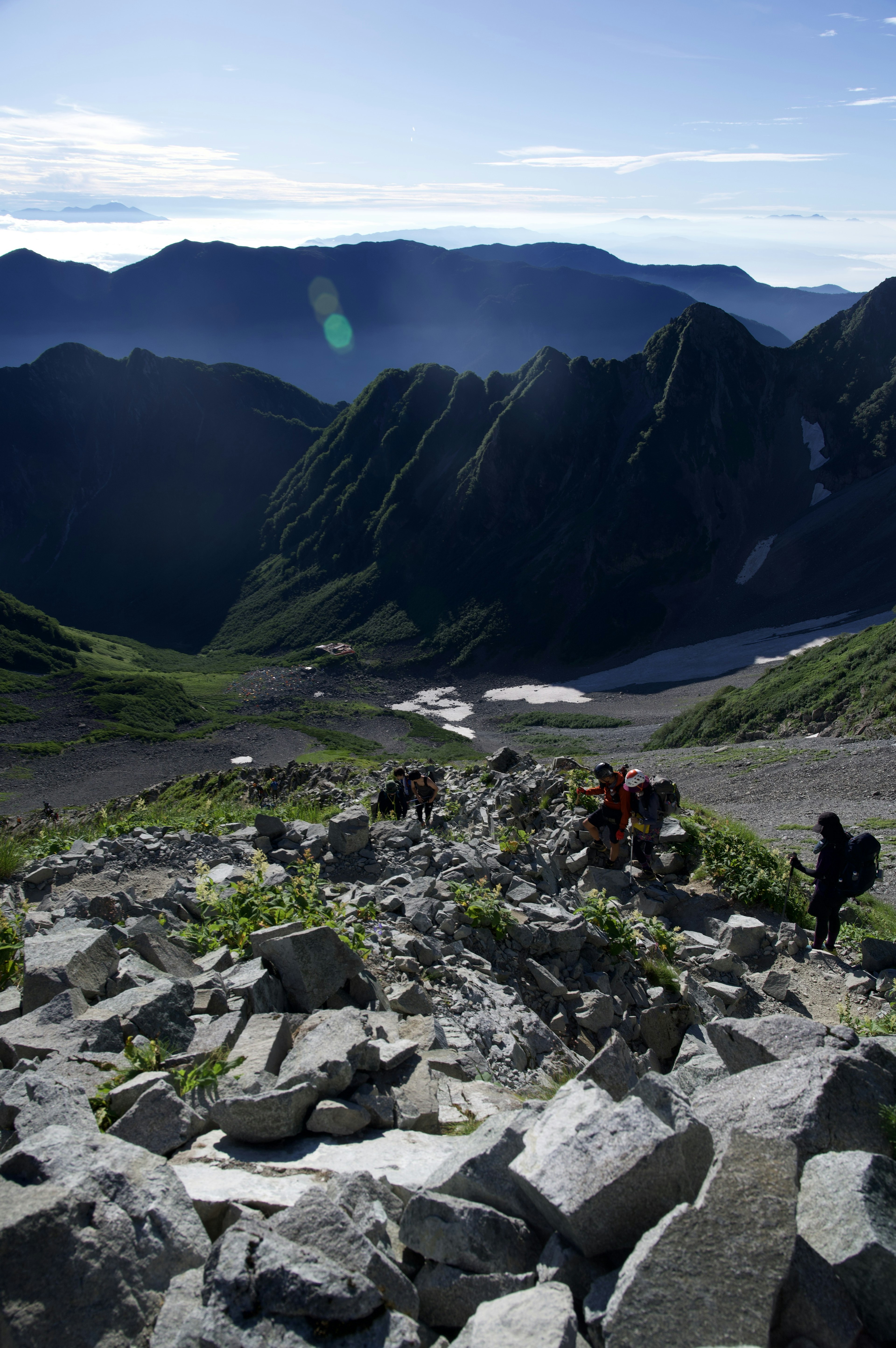 Randonneurs gravissant un sentier de montagne rocheux avec une verdure luxuriante