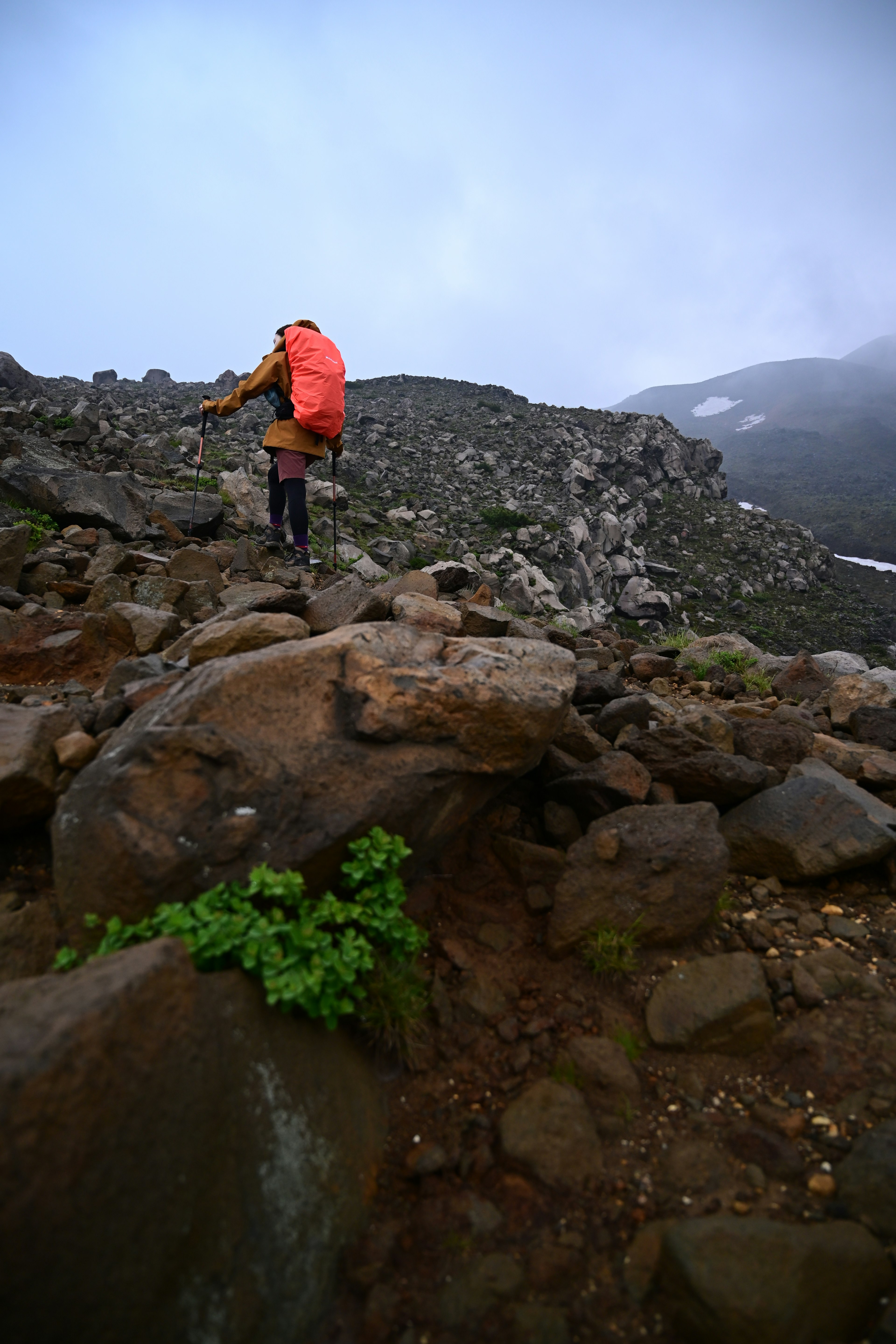 Hiker climbing a rocky mountain trail with foggy background