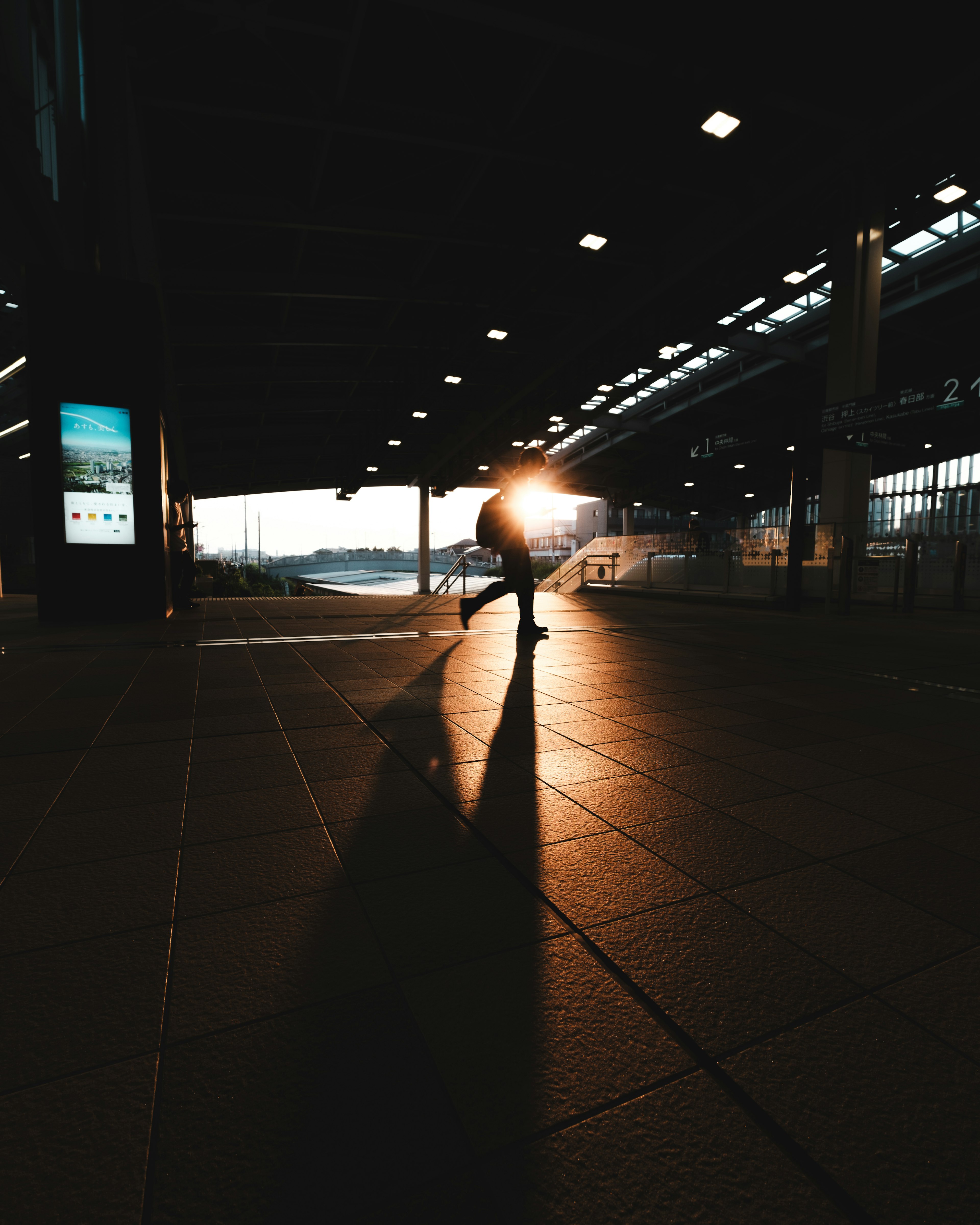 夕日を背にした人物のシルエットが映る駅の内部