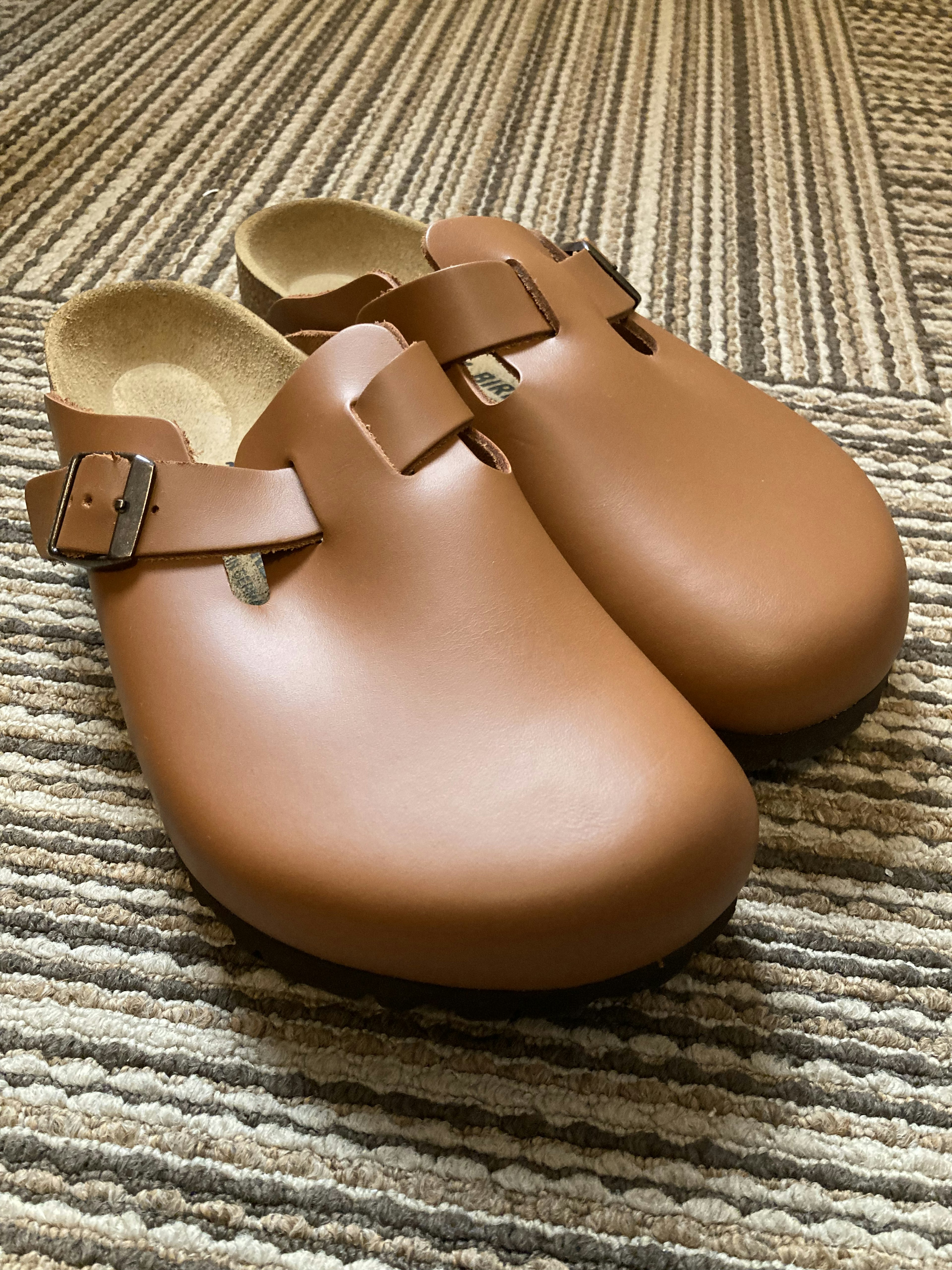 Pair of brown wooden clogs displayed on a textured surface