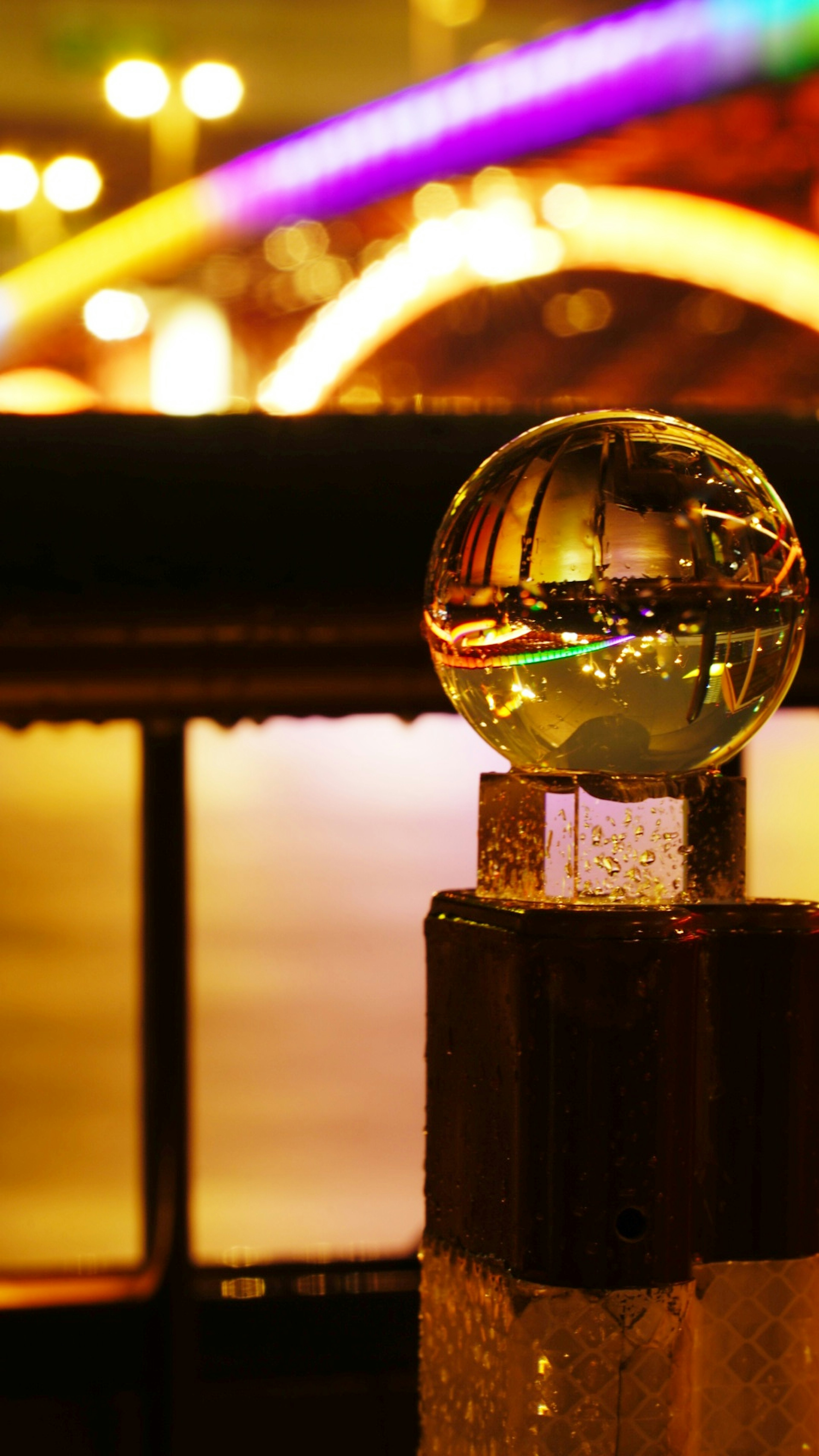 Crystal ball reflecting a bridge and water at night