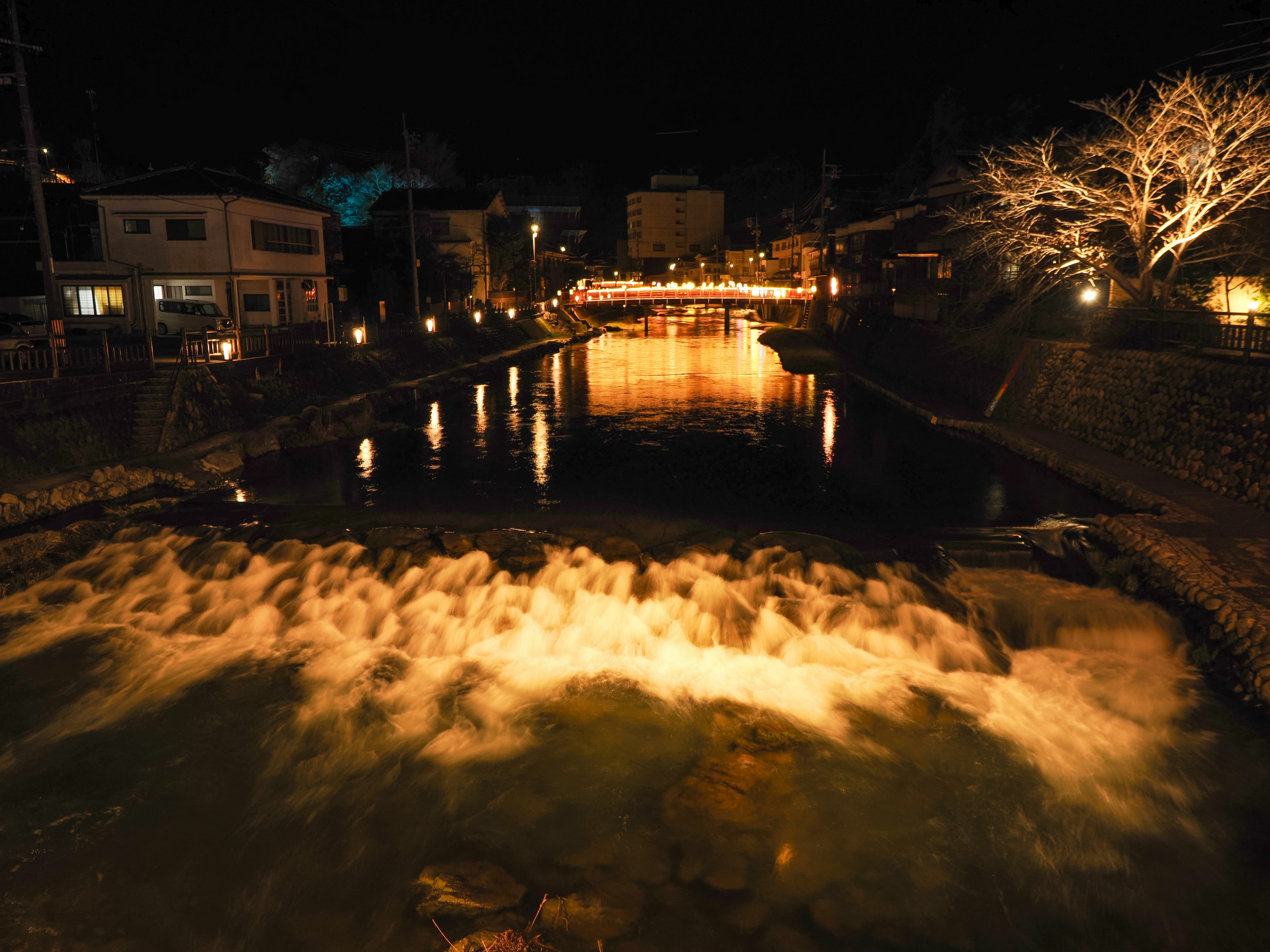 Schöne Aussicht auf einen Fluss und eine beleuchtete Stadtlandschaft bei Nacht