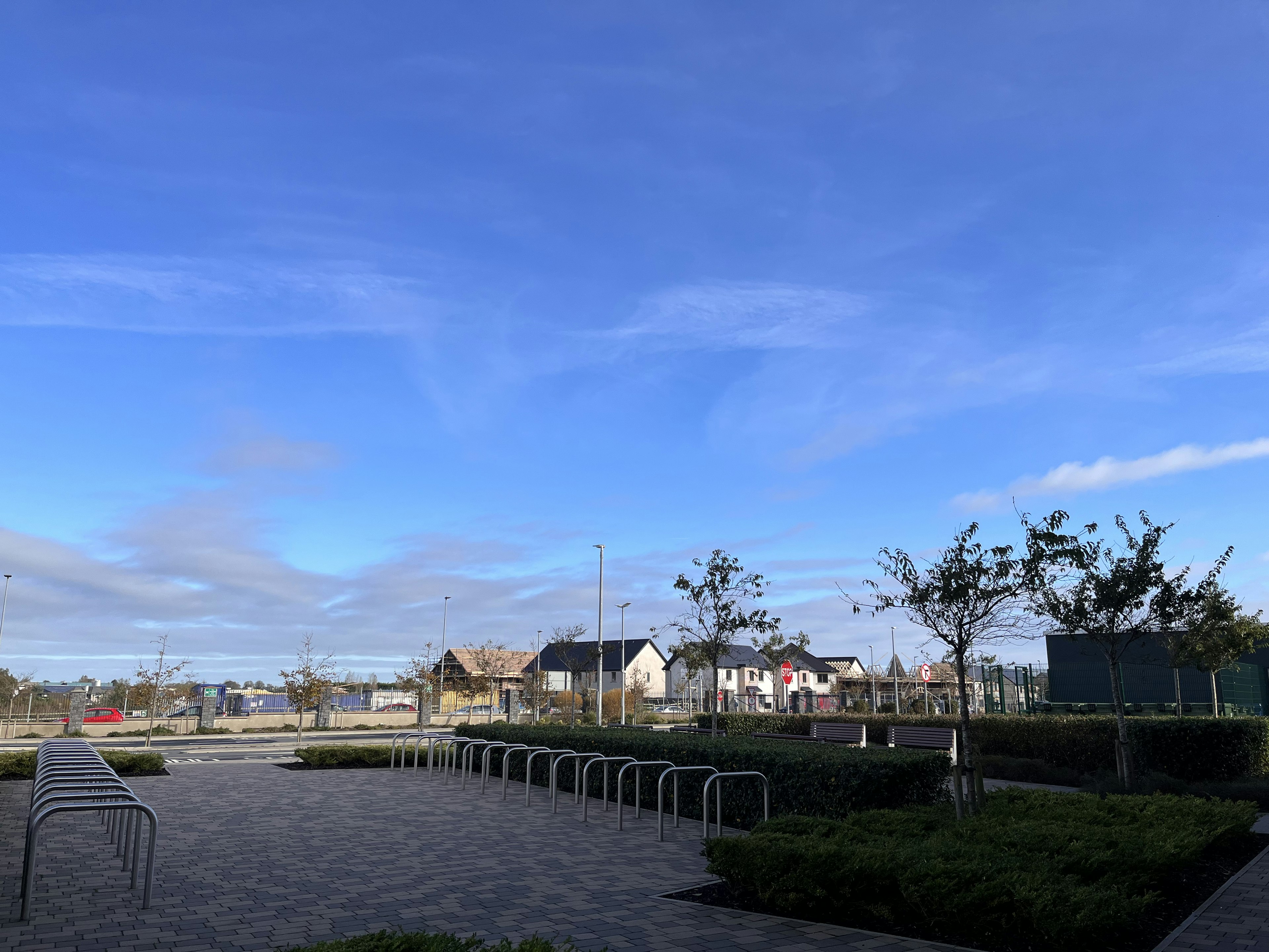 Landscape featuring benches under a blue sky with houses in the background