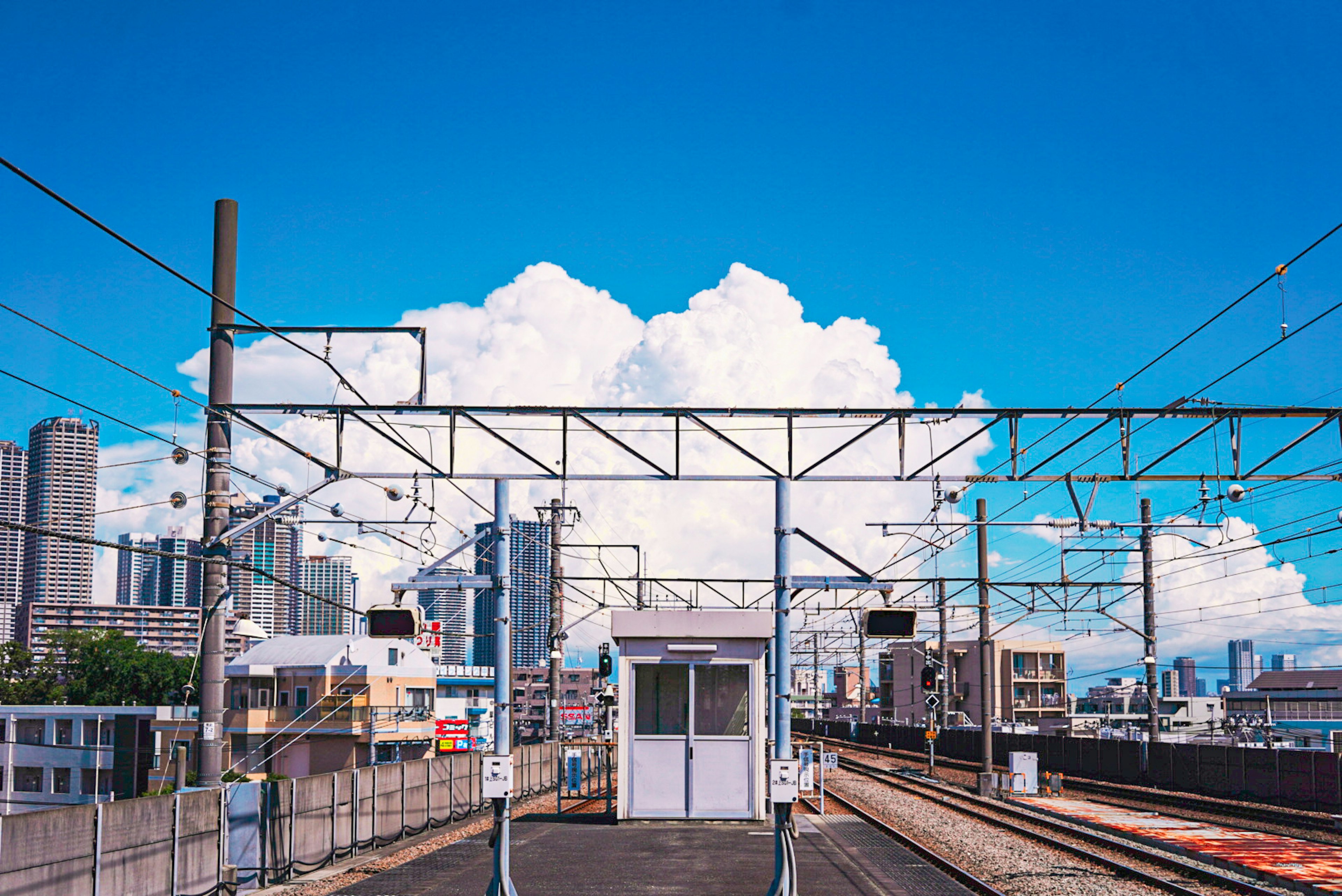 一幅鐵路車站的場景，藍天和白雲，展示車站建築和軌道