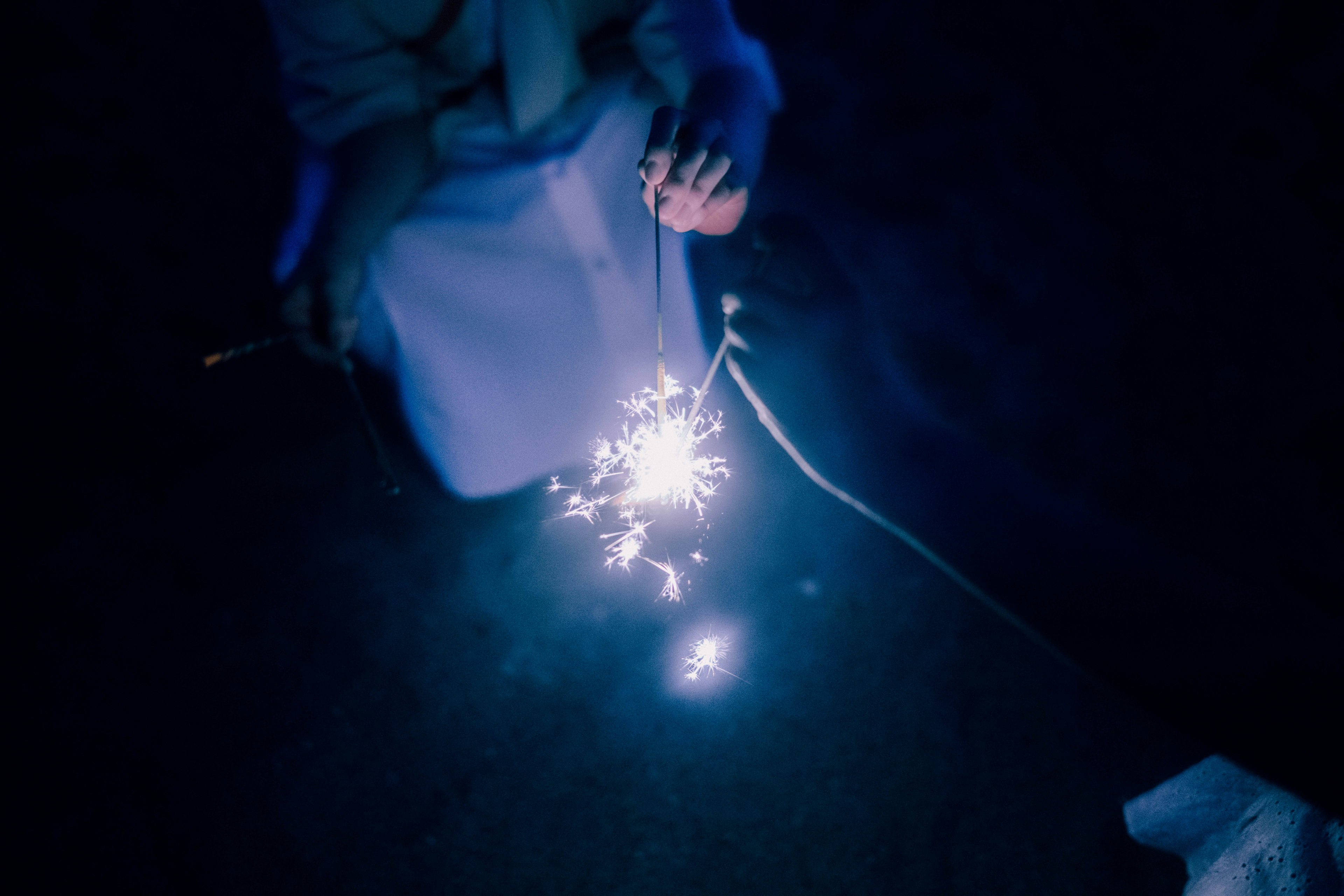 Eine Hand, die ein Feuerwerk gegen einen dunklen Hintergrund hält