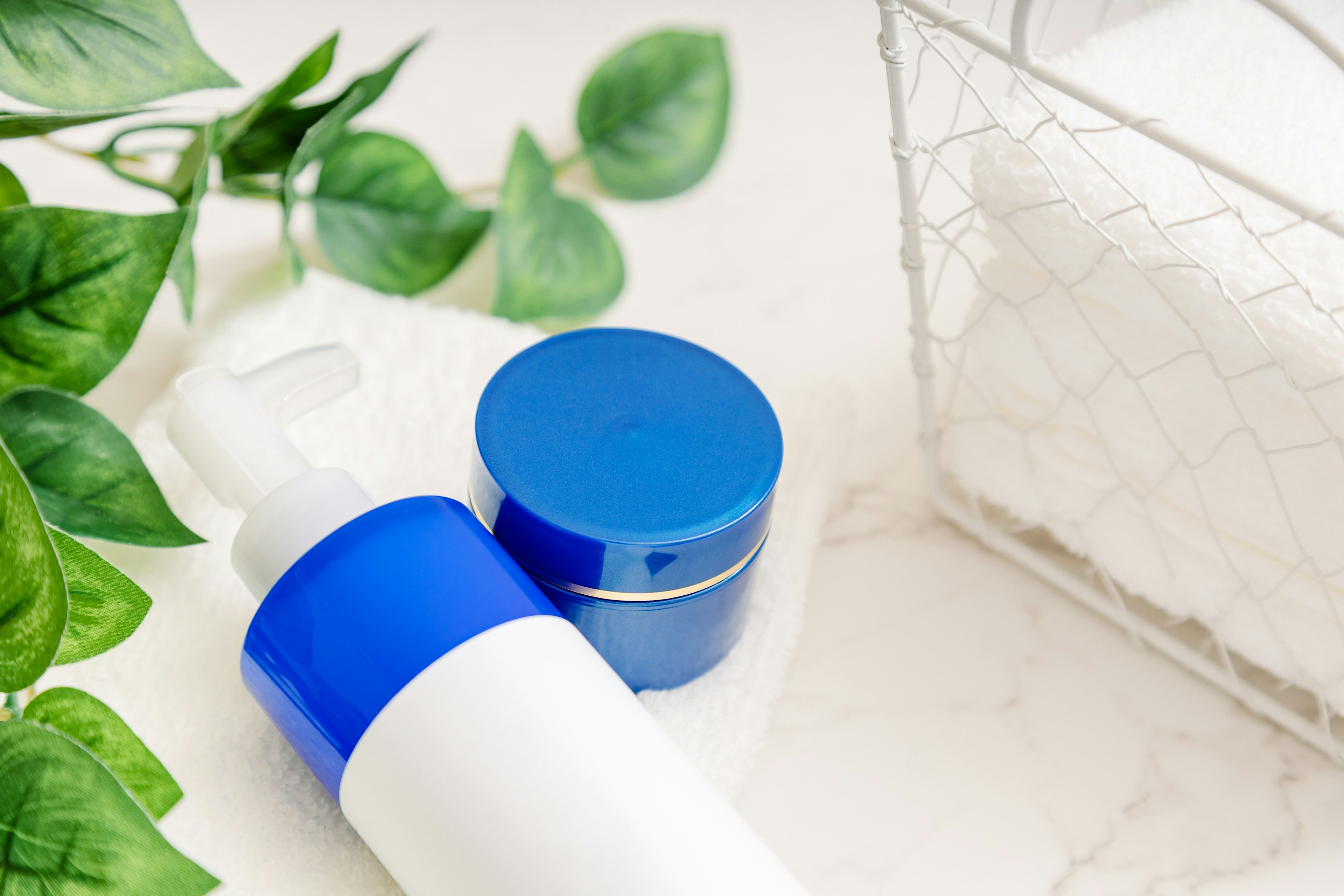 Image of skincare products with blue caps and green plants on a tabletop