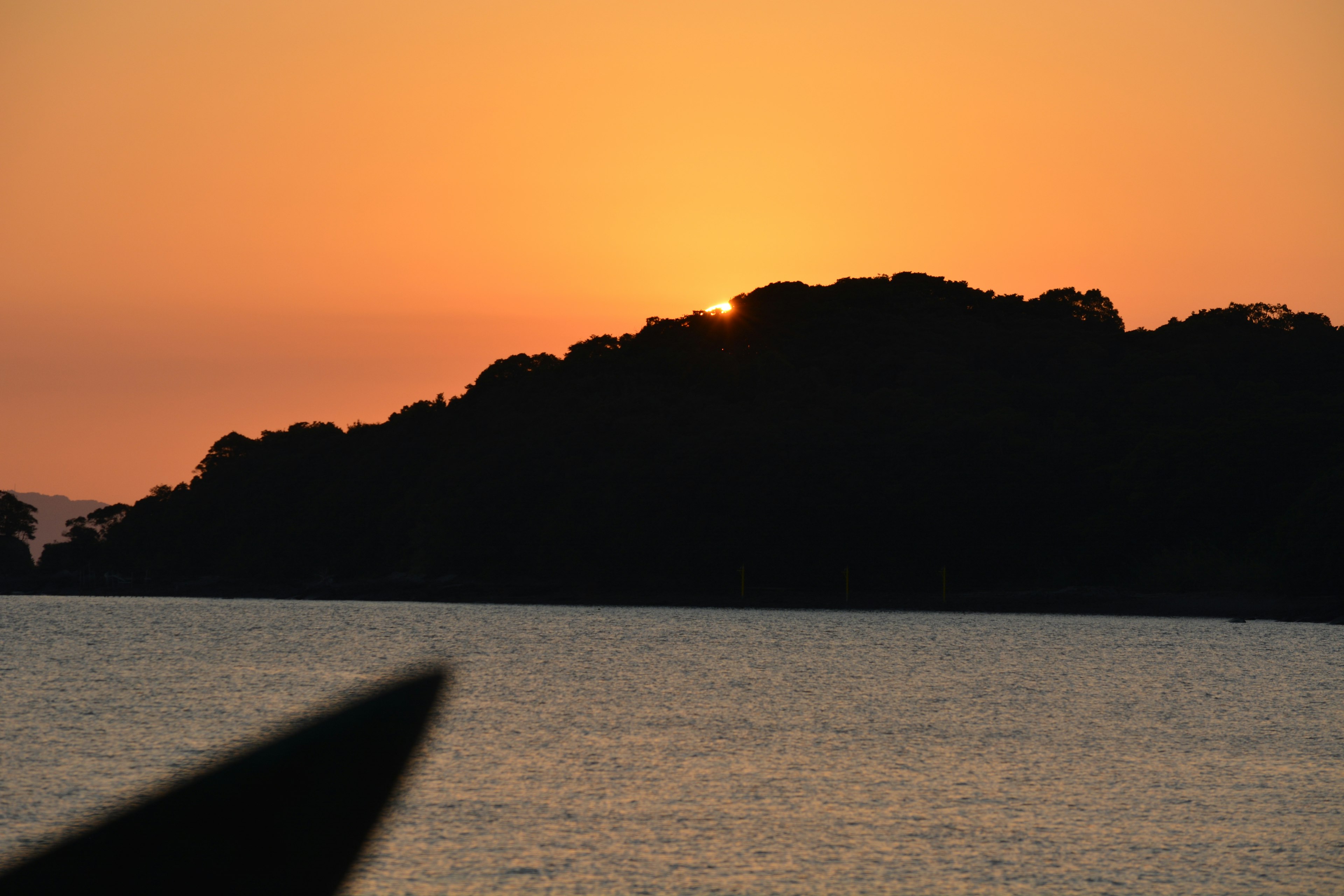 Coucher de soleil derrière une colline sur des eaux calmes