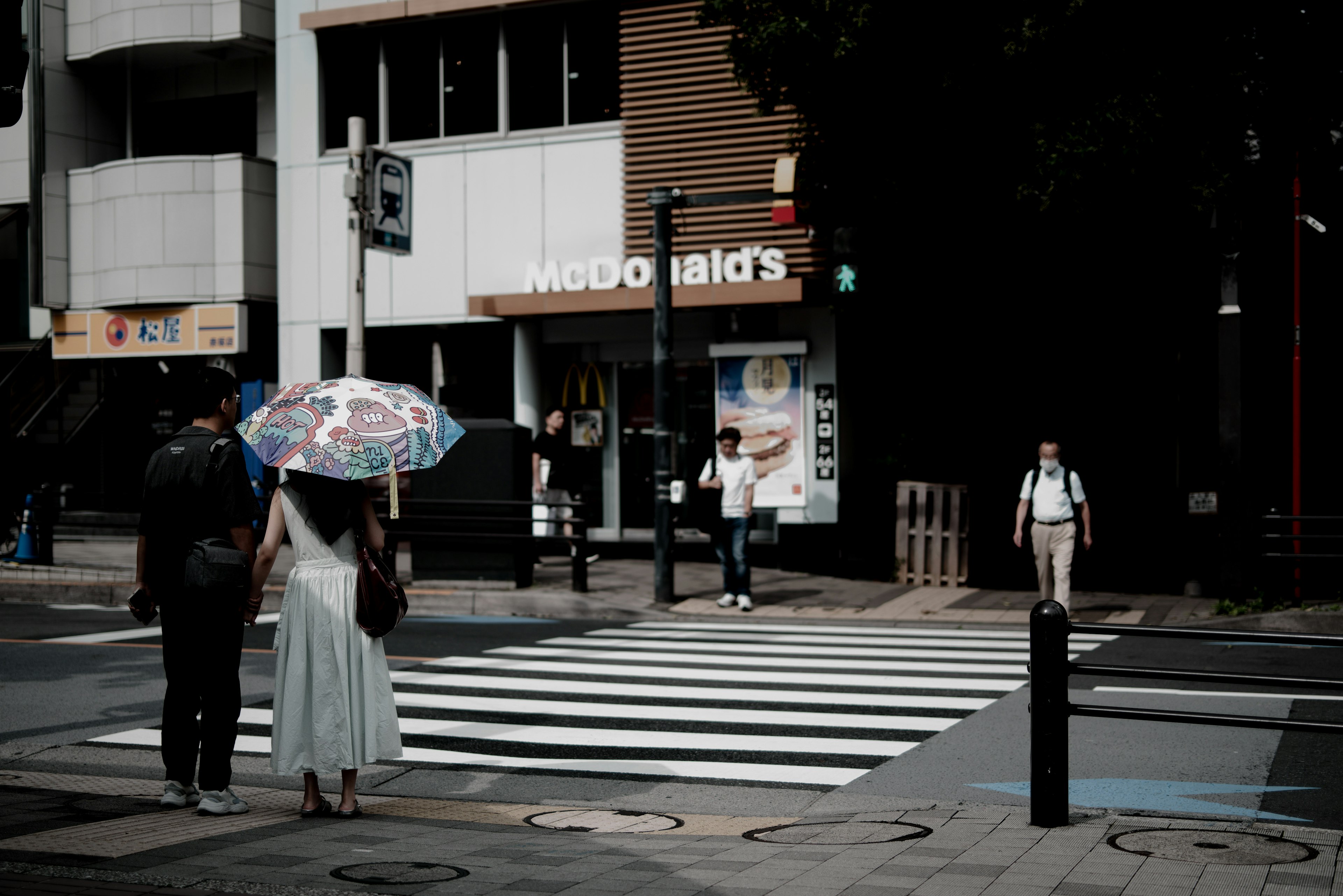 Un couple marchant sur un passage piéton avec un parapluie