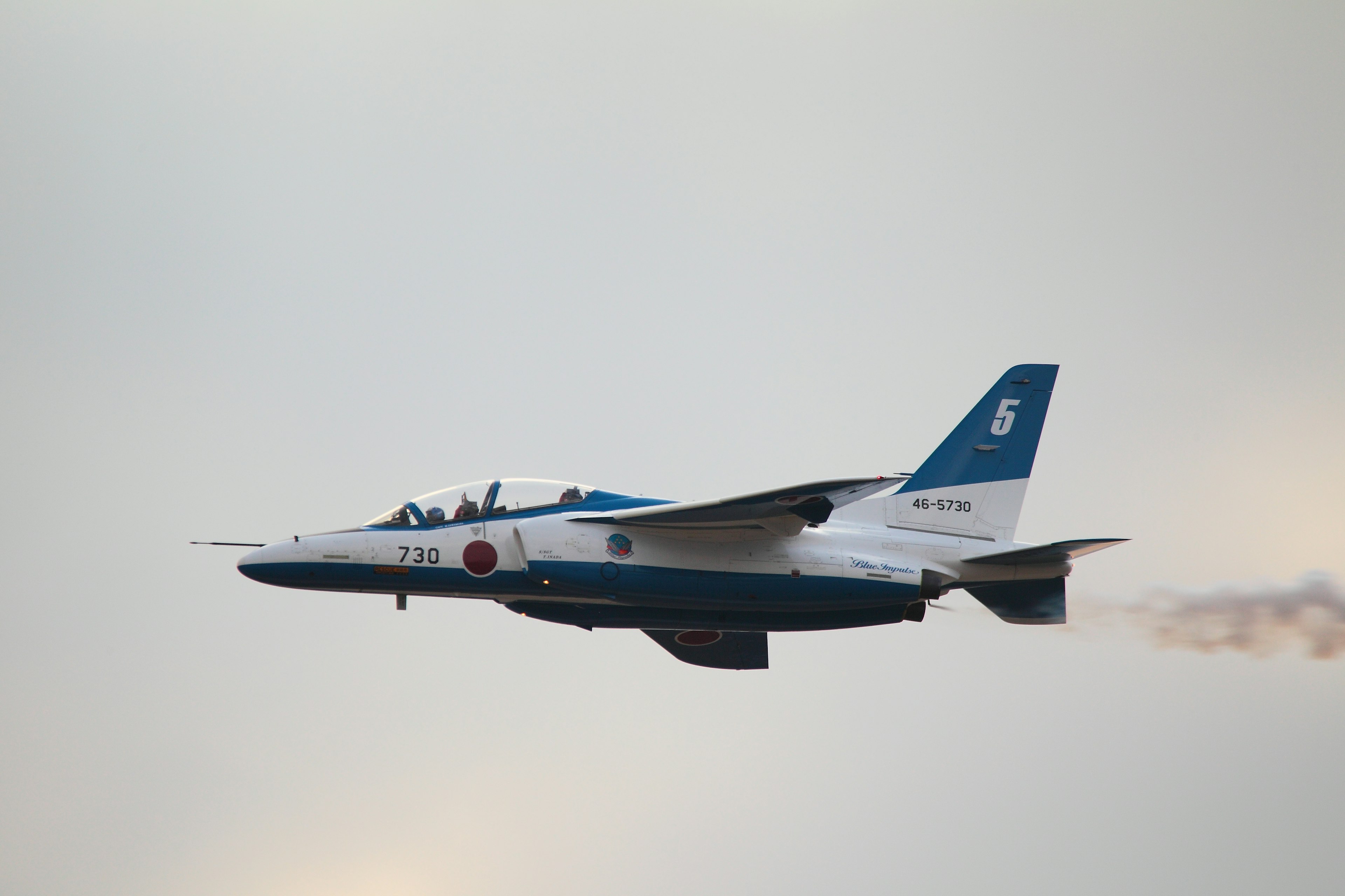 A blue and white fighter jet flying in the sky