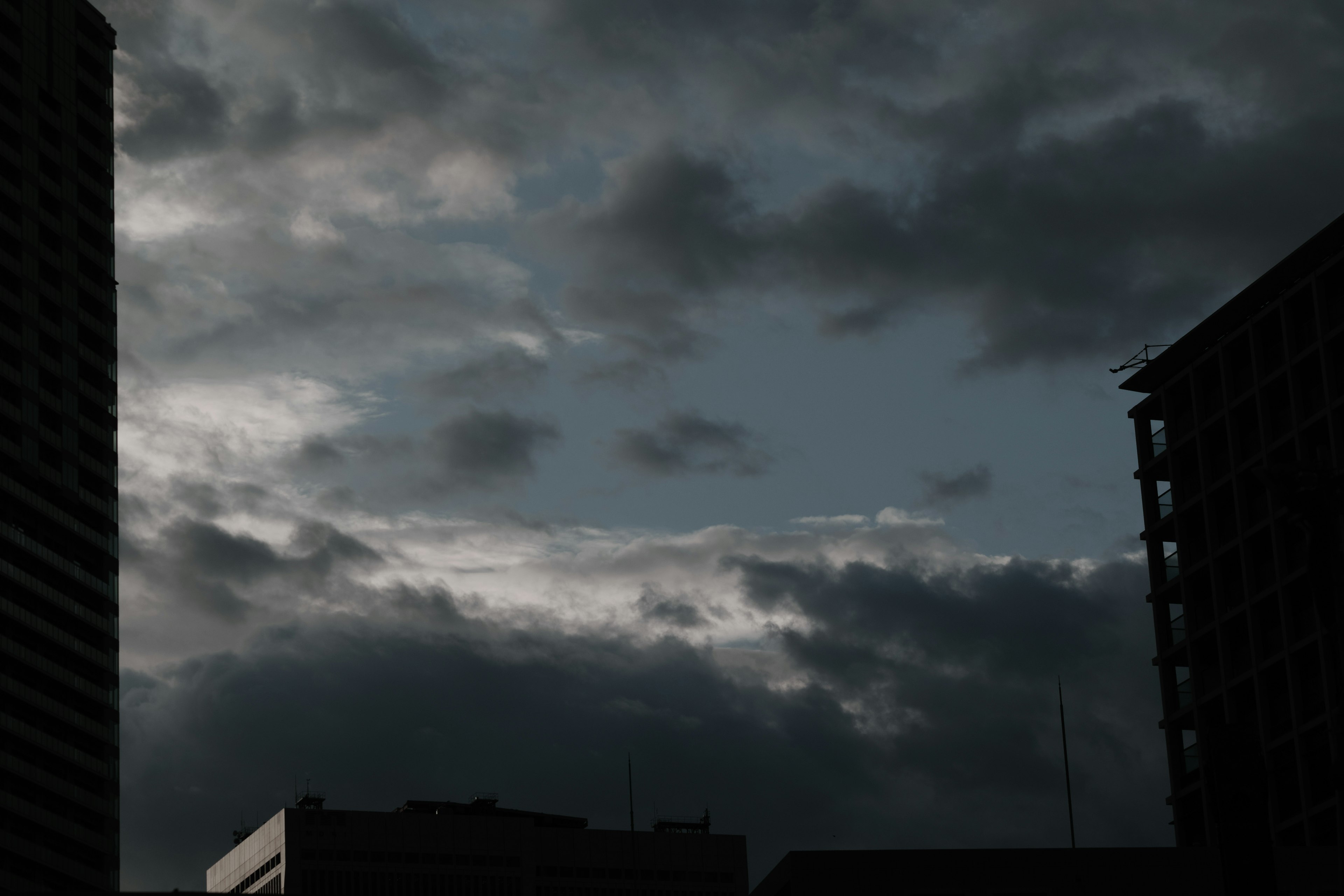 暗い雲に覆われた空とシルエットのビル