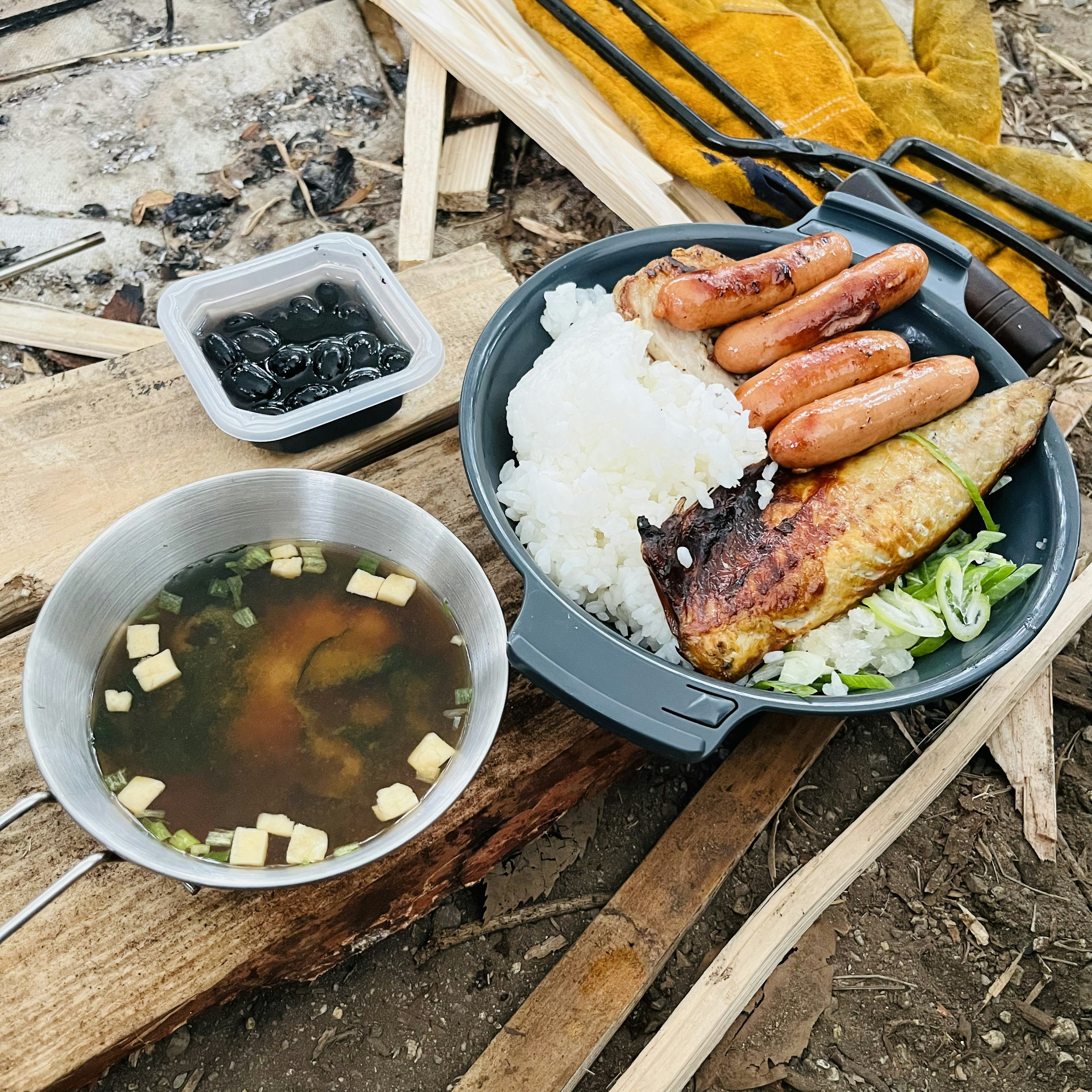 Un plato de comida de camping con arroz salchichas y pescado a la parrilla