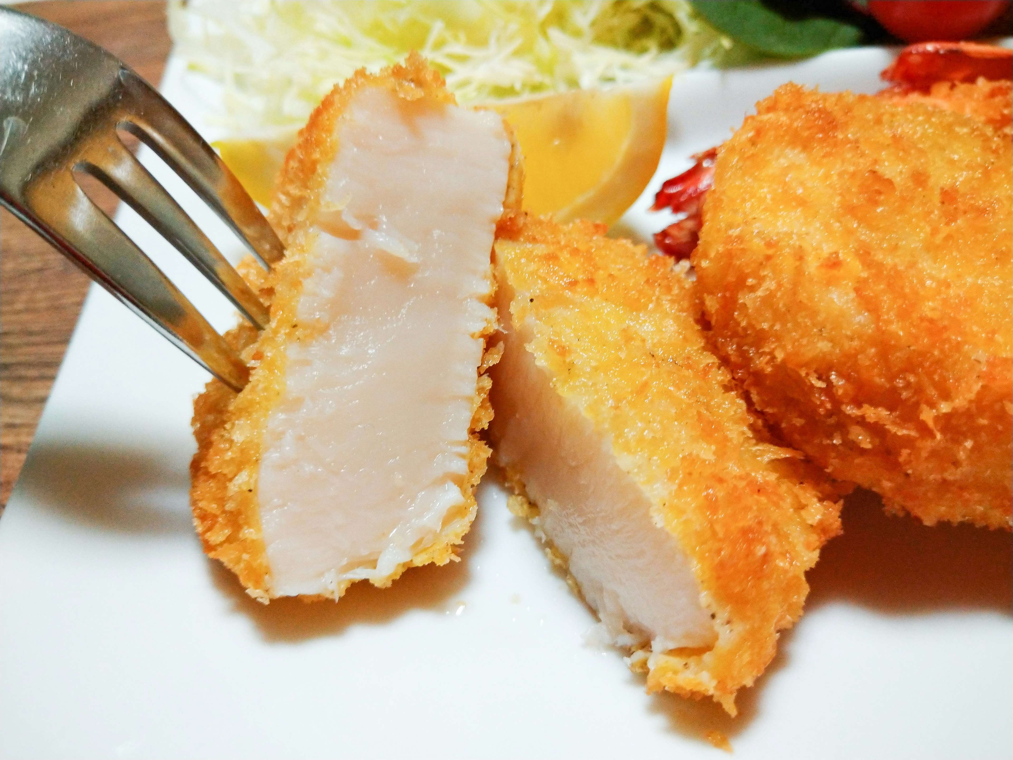 Primo piano di una cotoletta di pollo fritta con una forchetta su un piatto