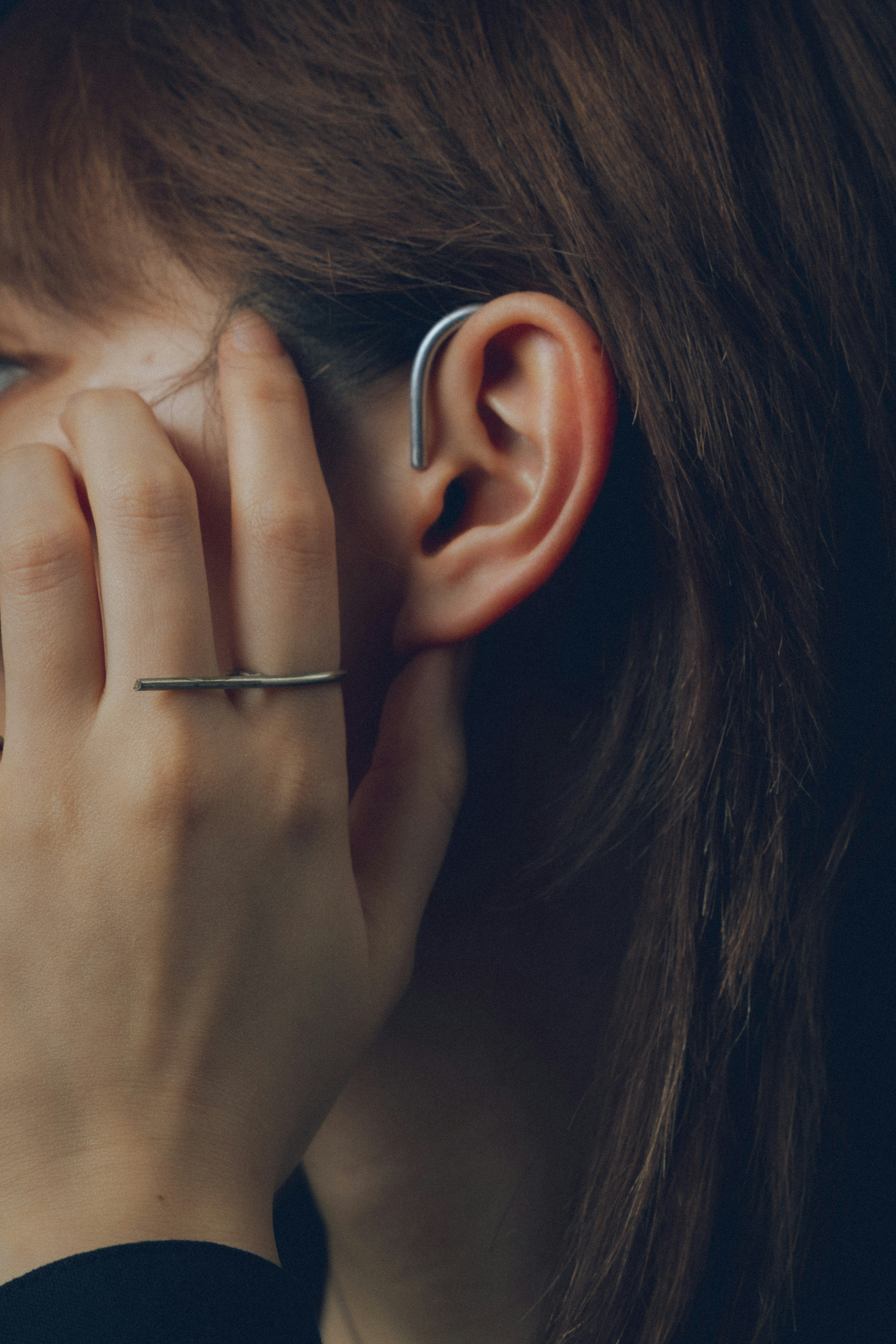 Close-up of a woman's hand near her ear with an earbud