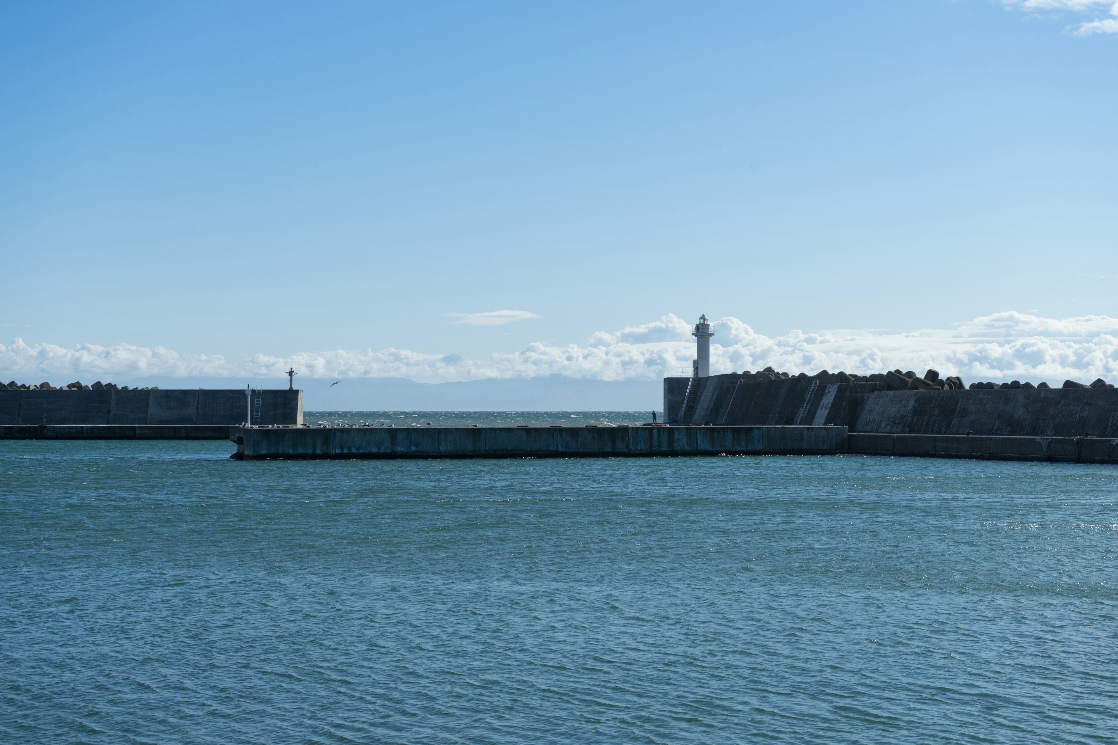 Küstenansicht mit einem Leuchtturm und ruhigem blauem Wasser