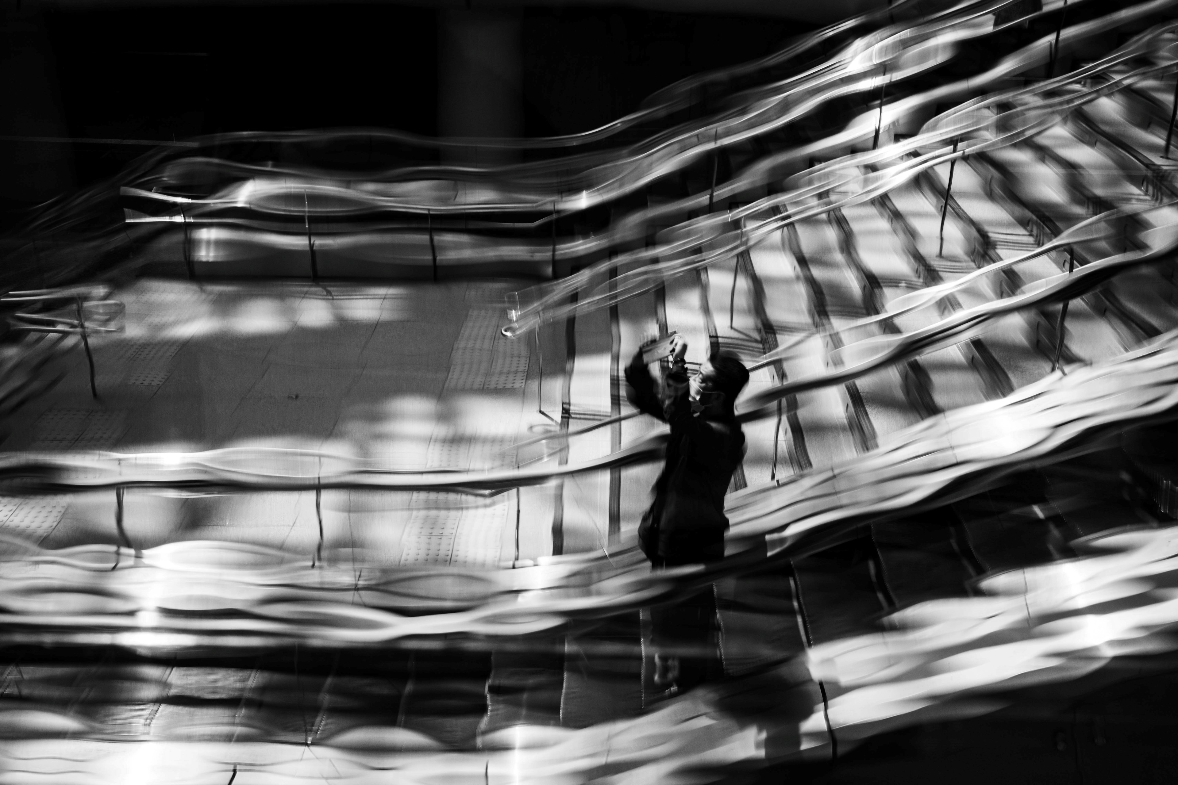 Black and white photo of a person posing on stairs with strong light and shadow contrast