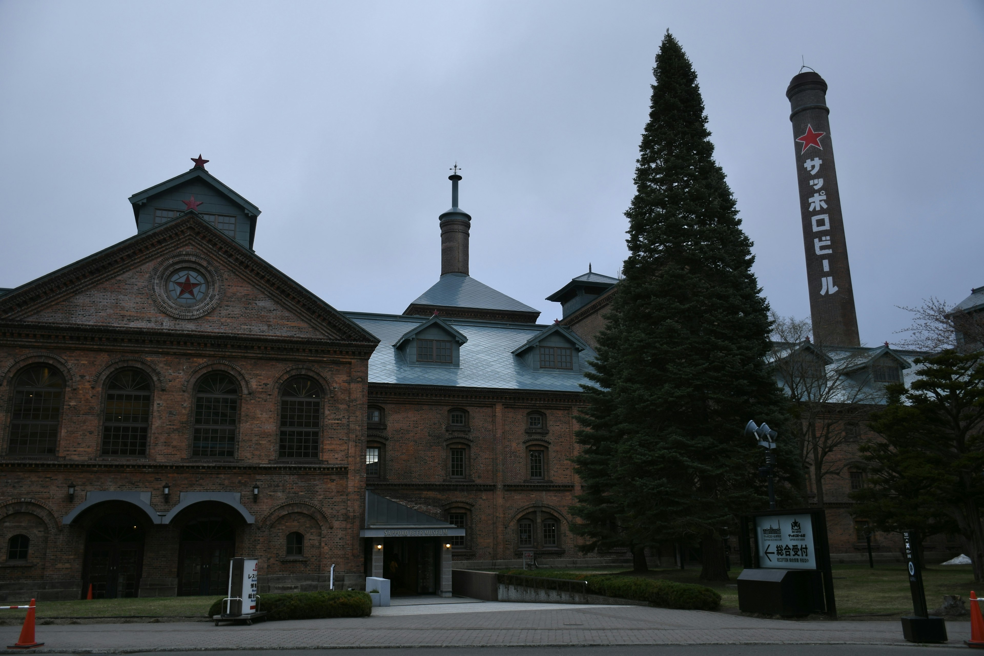 Historic Victoria building with a tall chimney and evergreen tree