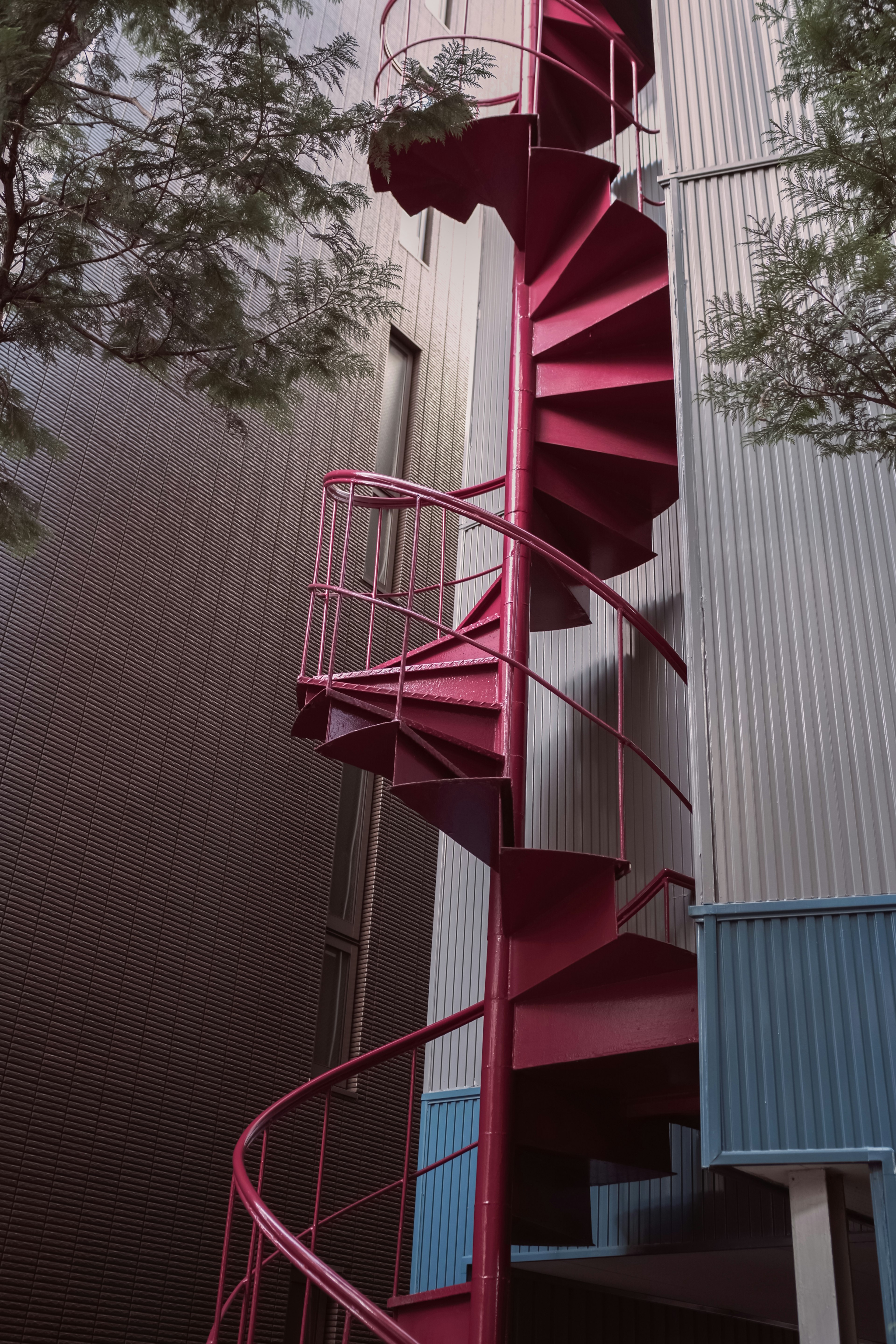 Imagen de una escalera de caracol roja unida al exterior de un edificio