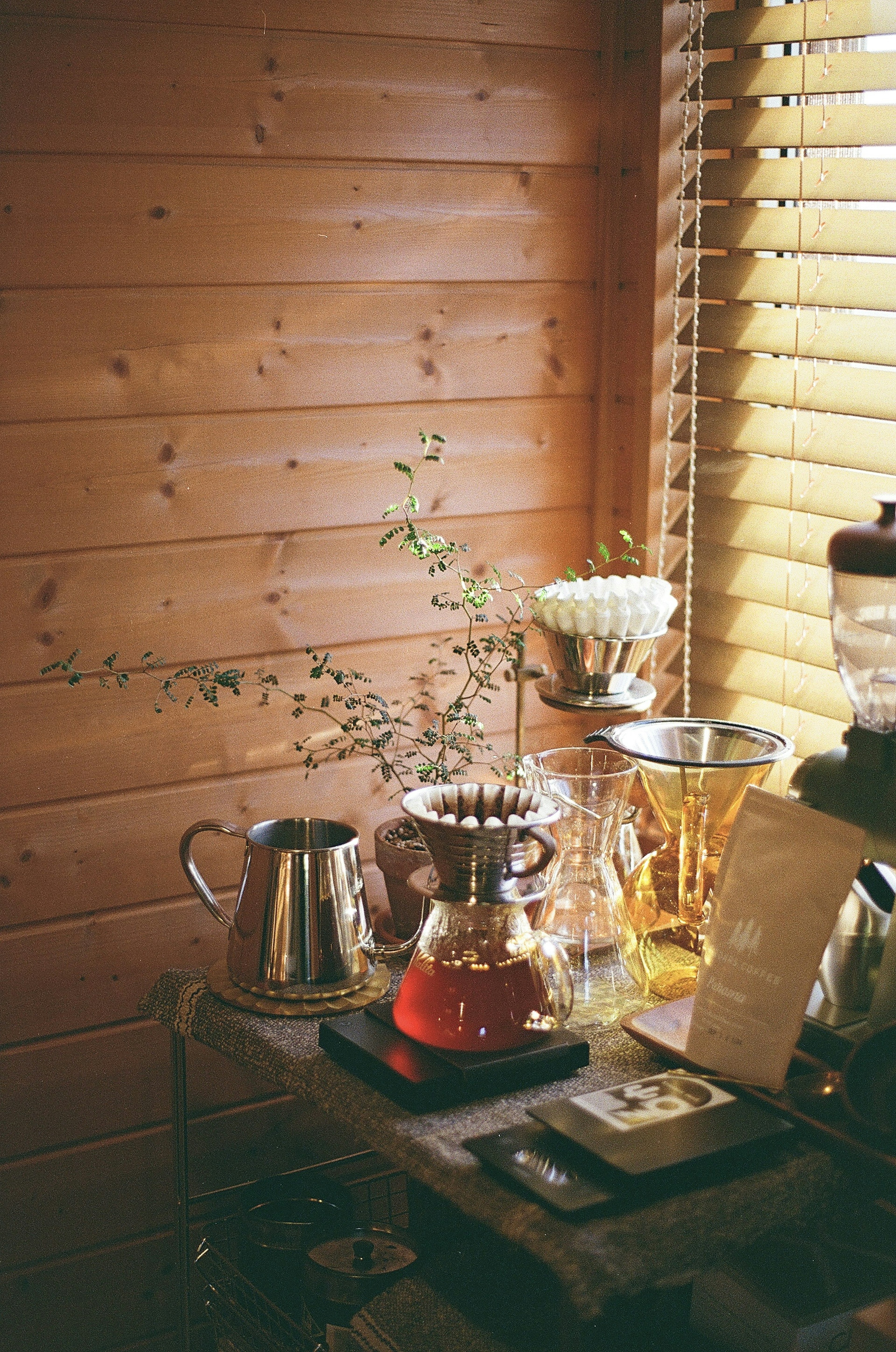 Cozy cafe corner with tea set and vase against wooden wall