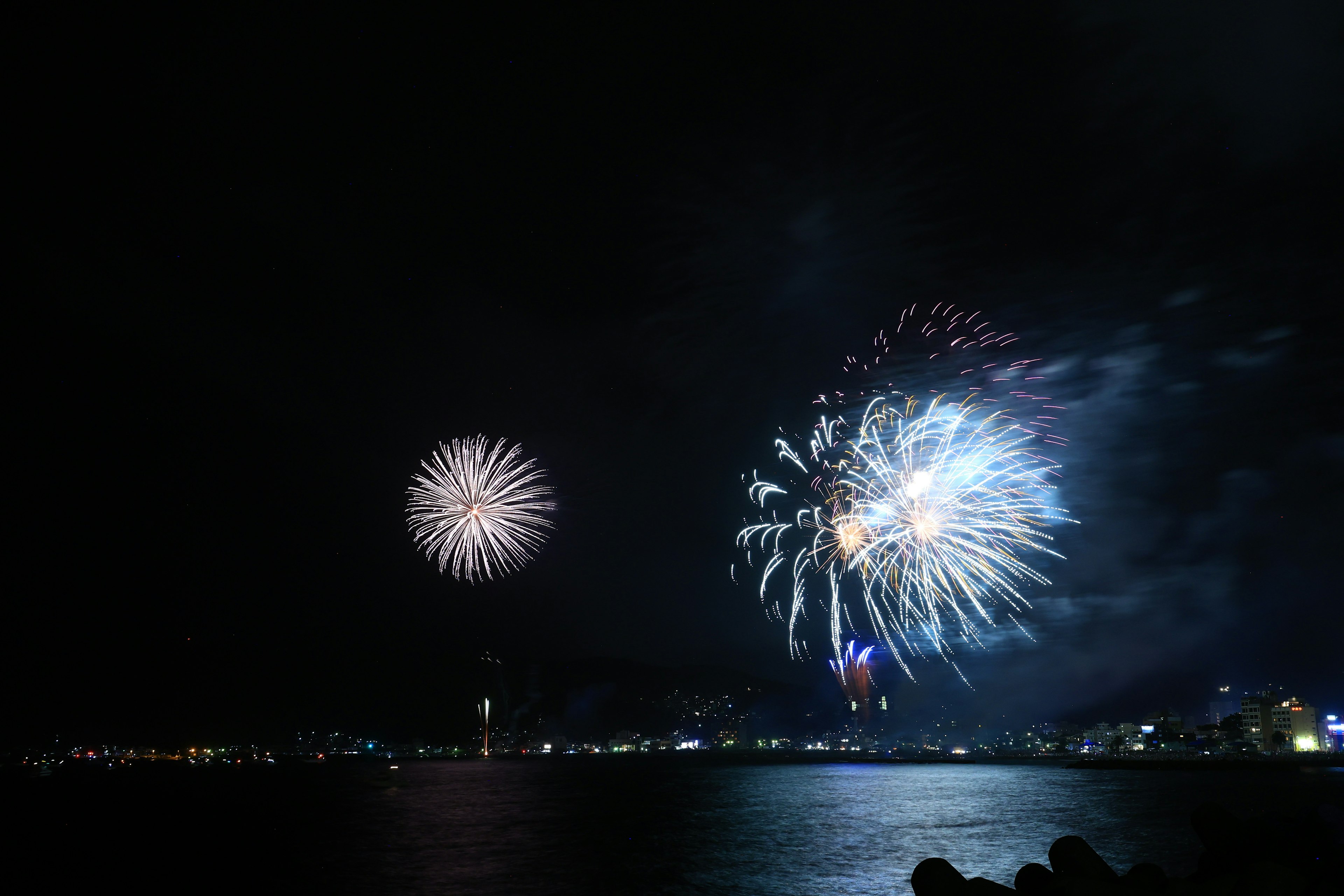 夜空中绚丽的烟花表演，水面上倒映着光彩