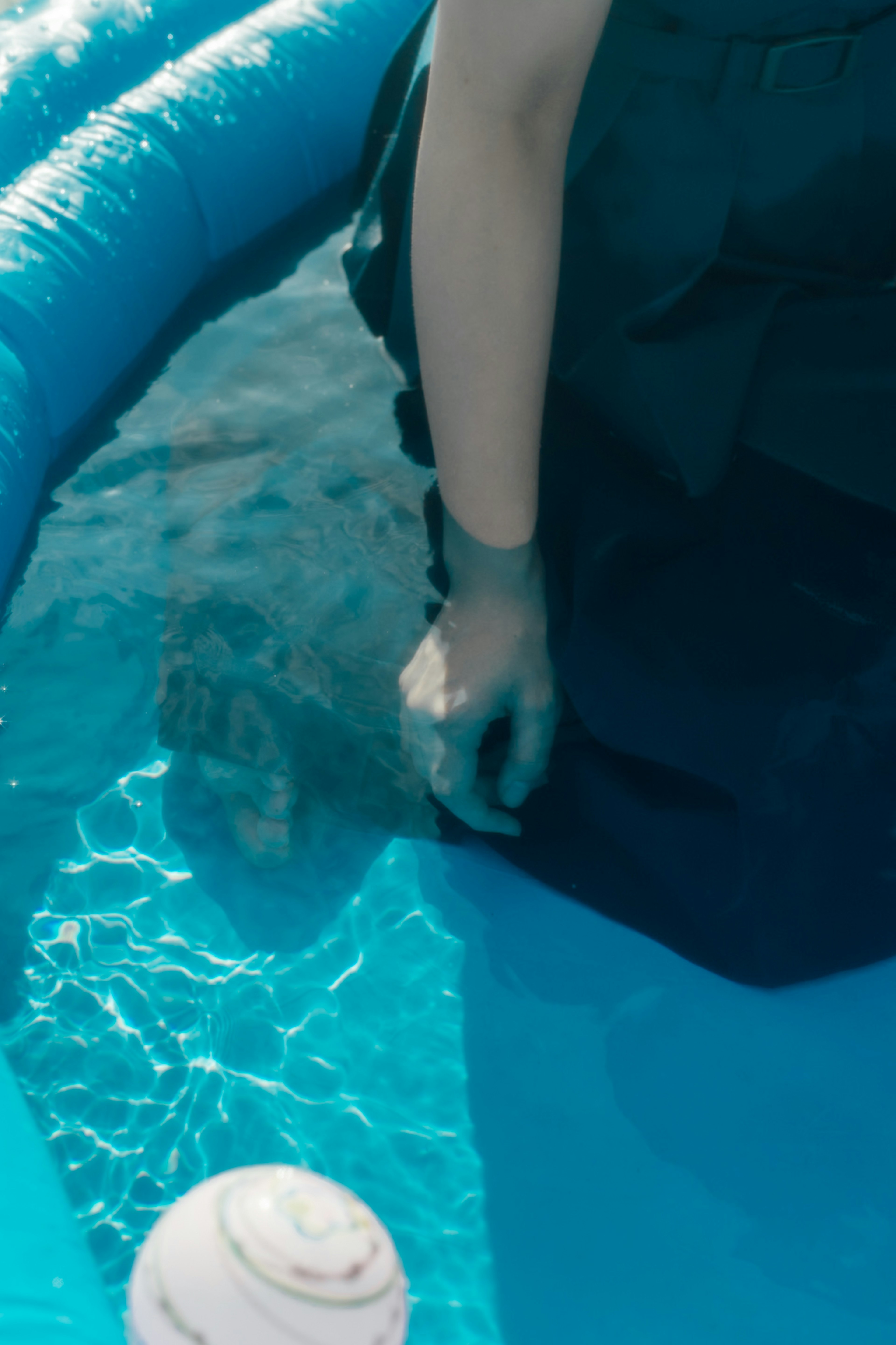 Un braccio di una persona immerso nell'acqua blu di una piscina