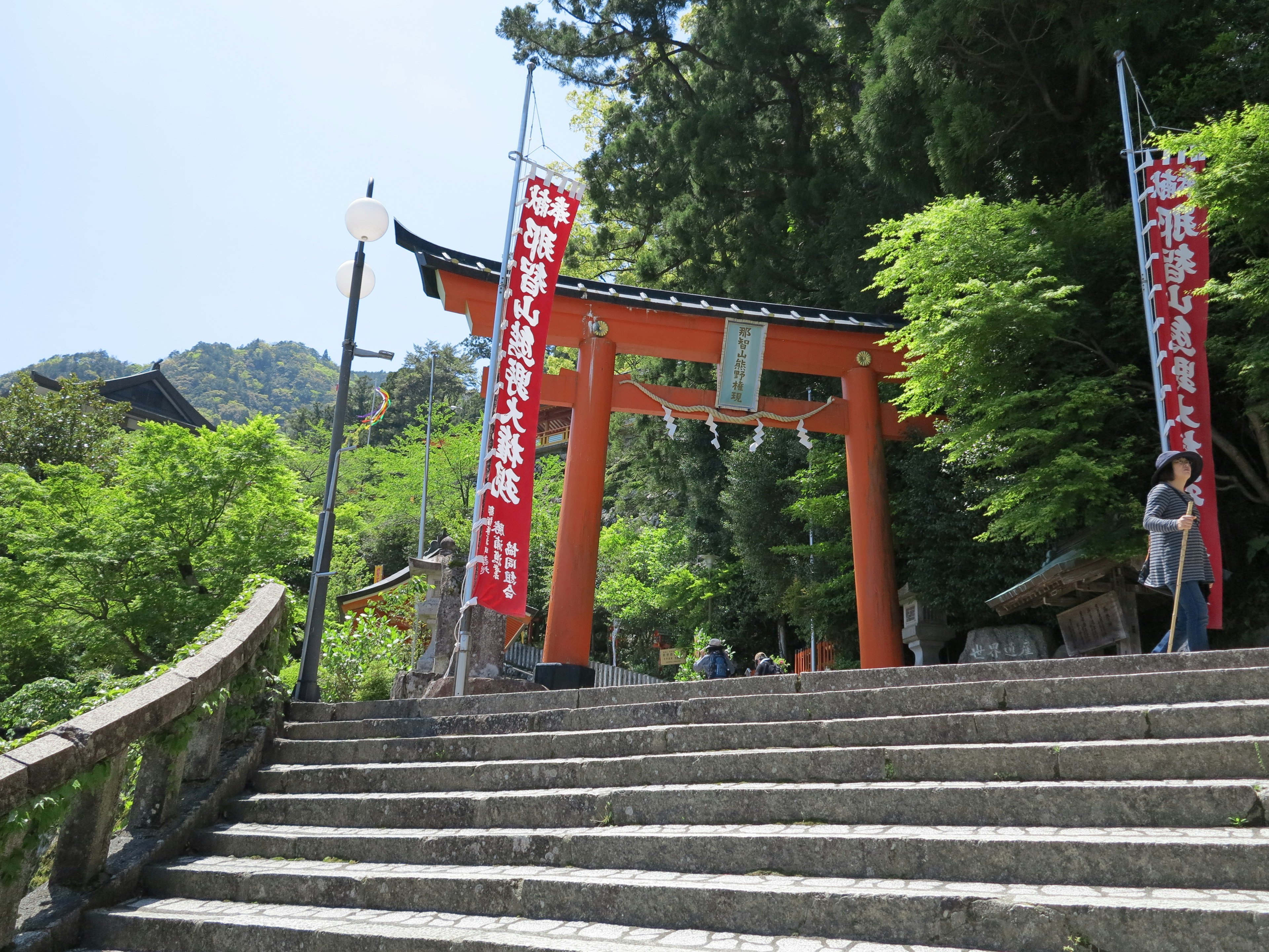 Porte torii rouge et escaliers entourés de verdure à l'entrée d'un sanctuaire