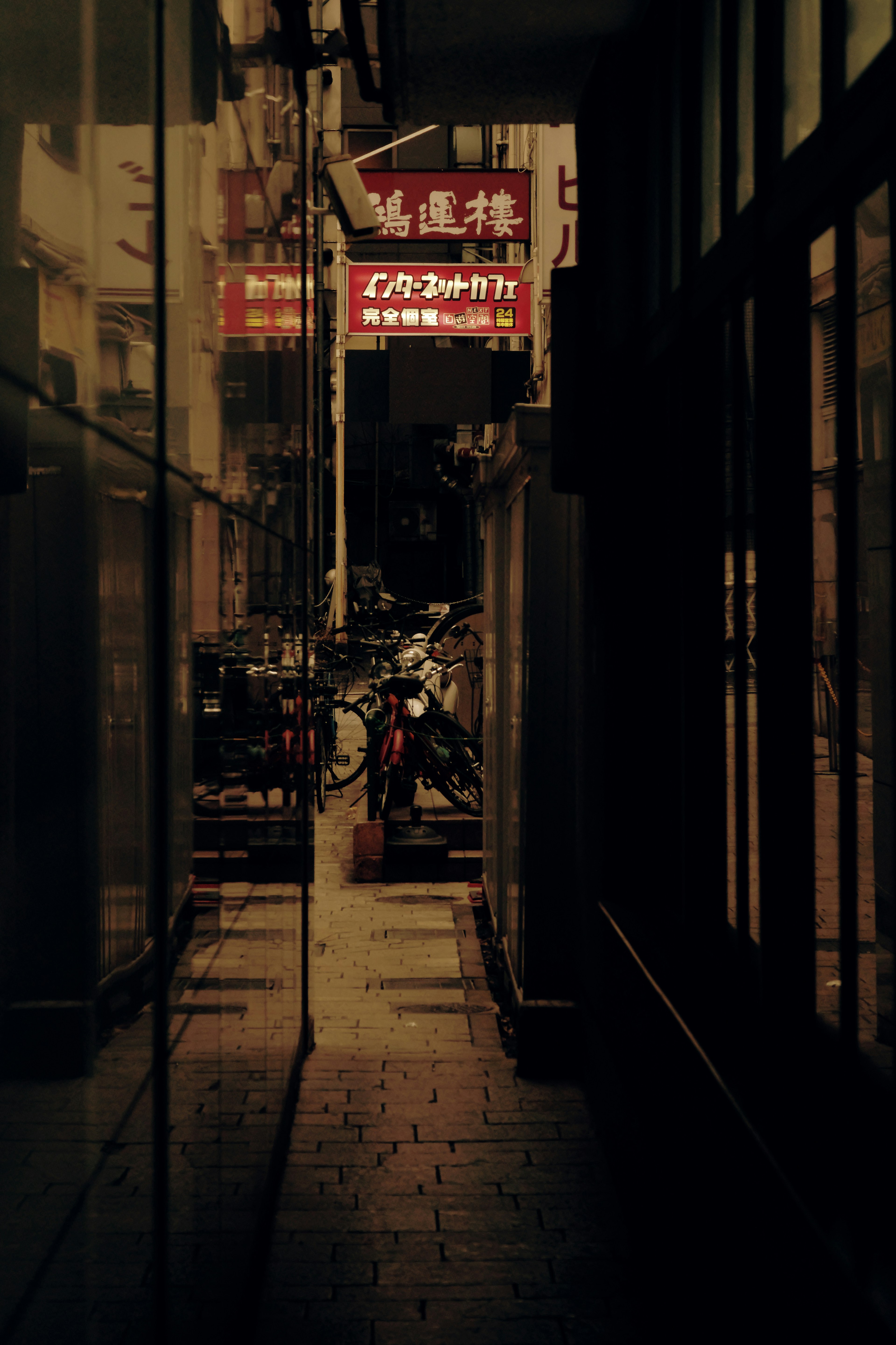 Narrow alley with parked bicycles and red neon signs