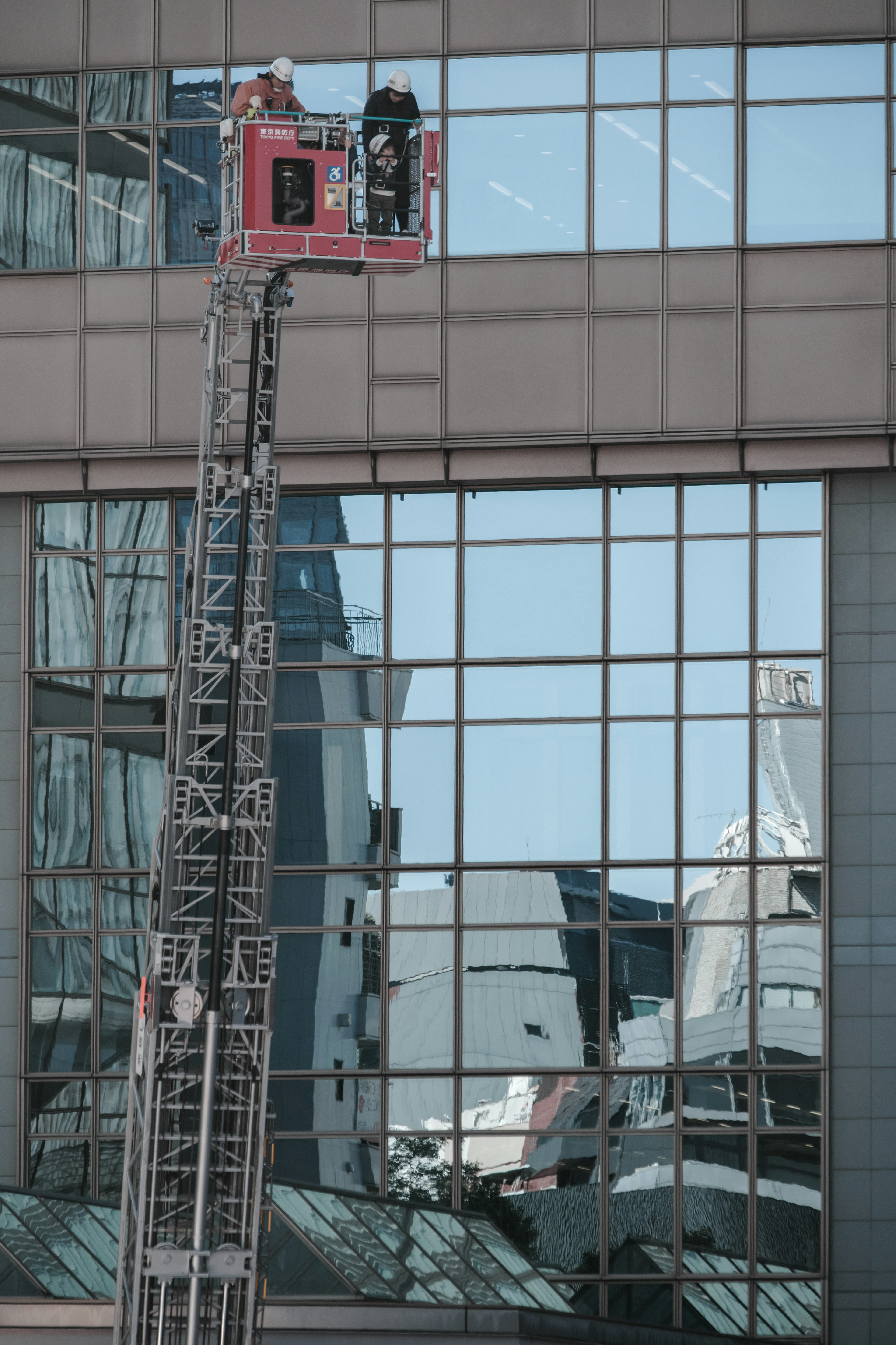 Two workers on a lift cleaning the windows of a high-rise building