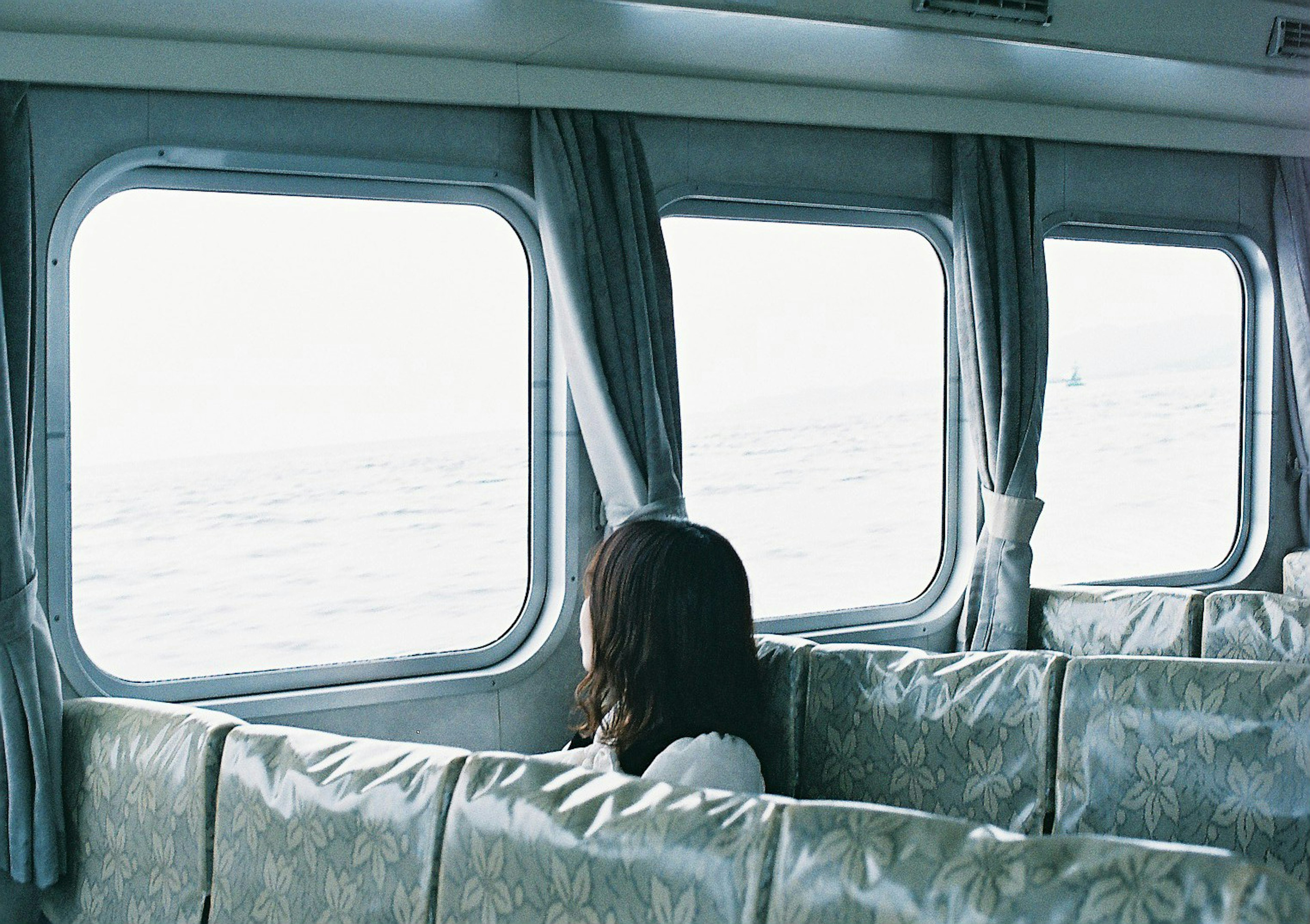 Mujer mirando al mar desde un asiento dentro de un barco