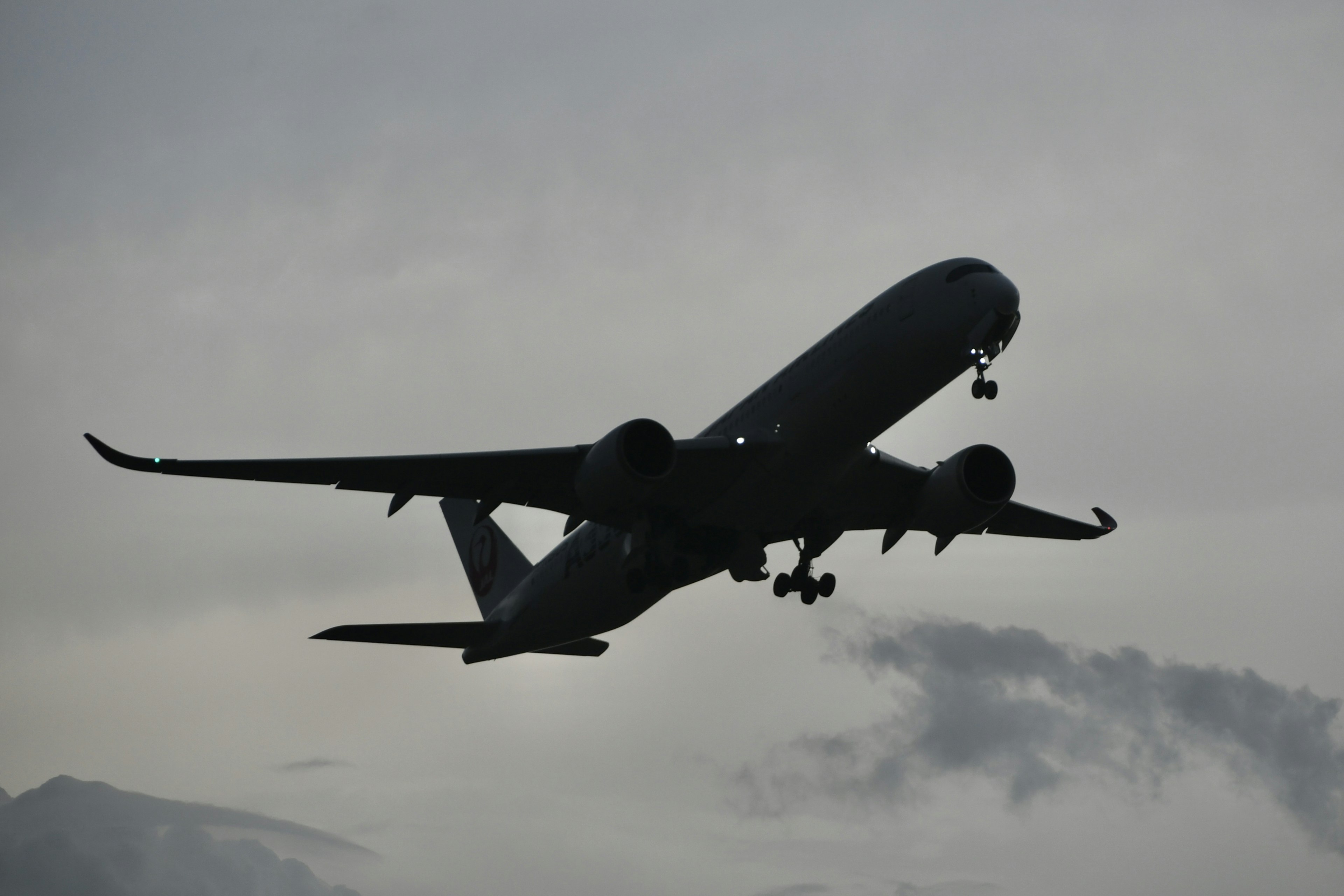 Airplane silhouette flying through cloudy sky